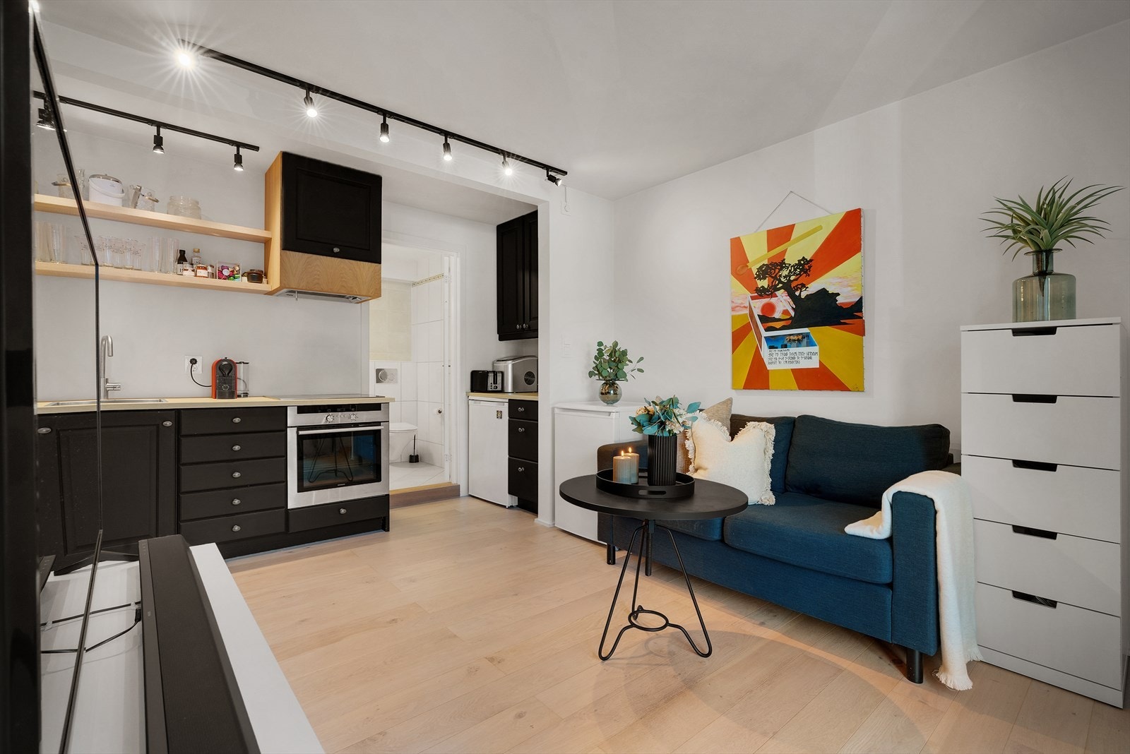 Kjøkkenet har mørke profilerte fronter og integrerte hvitevarer, inkludert stekeovn og induksjonsplatetopp, som gjør matlagingen til en enkel og hyggelig opplevelse Galleribilde