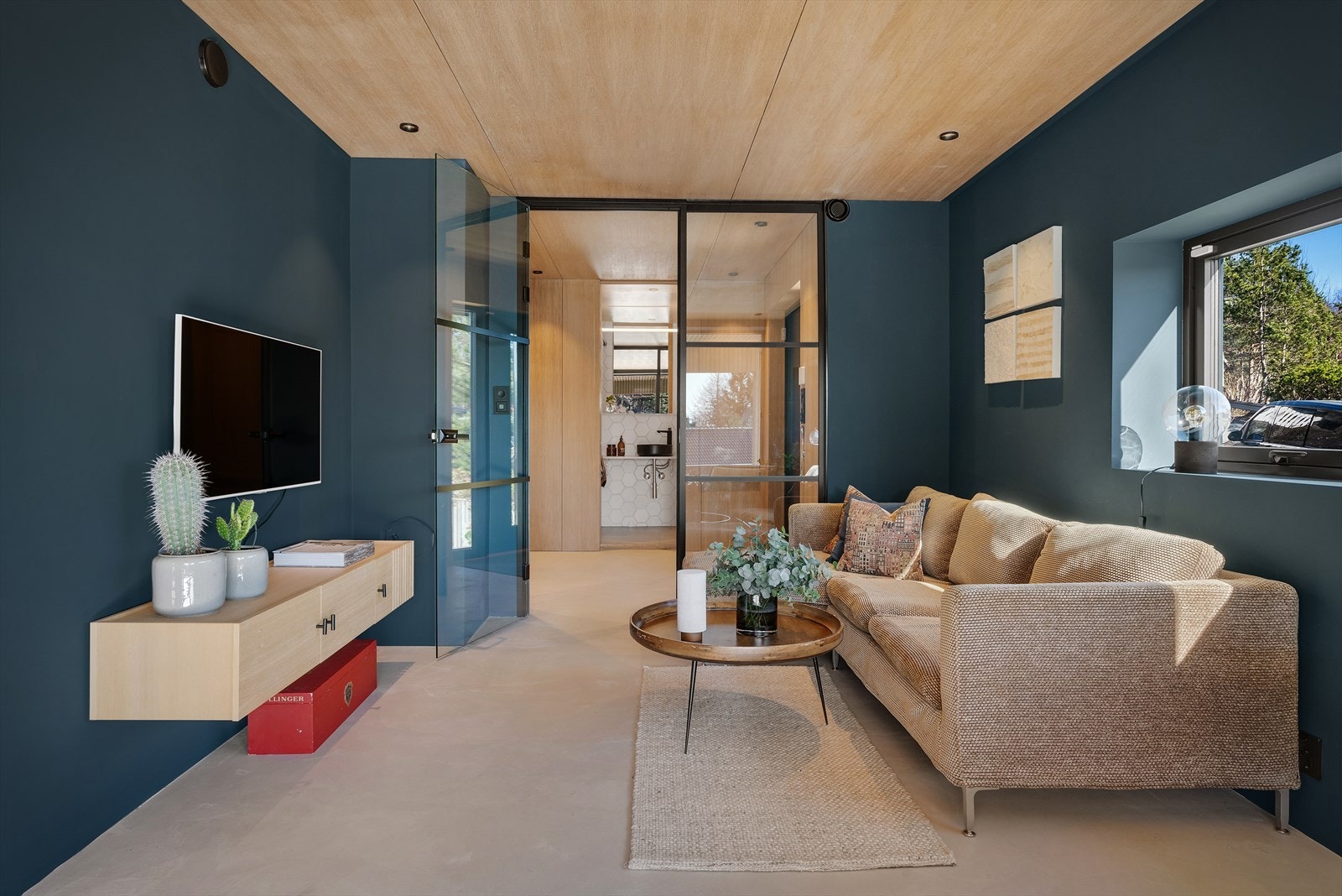 Like til venstre for entréen finner du en innbydende TV-stue, hvor mikrosementen og finerplatene belagt med eik i himlingen og spotlights fortsetter Galleribilde