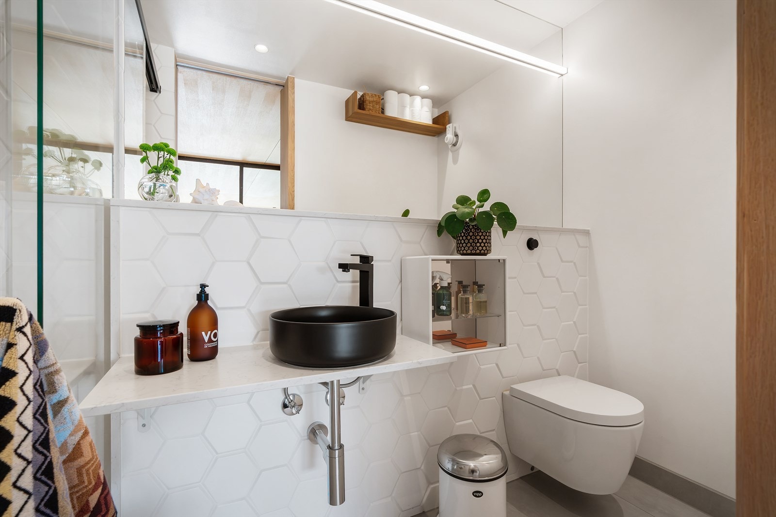 Det moderne badet i første etasje er utstyrt med eksklusive keramiske fliser på gulv og vegger, samt et stort spesialtilpasset speil som er med på å øke badets romfølelse Galleribilde