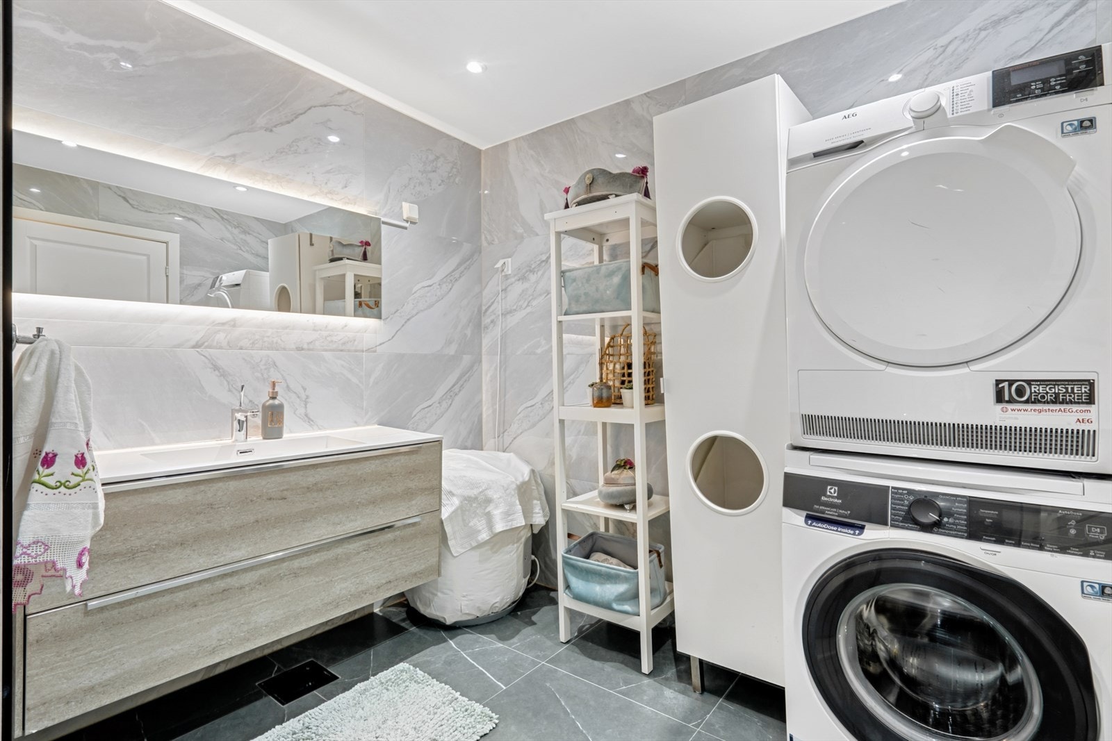 Innredet med servant med skuffer, speil med belysning og opplegg for vaskemaskin. Galleribilde