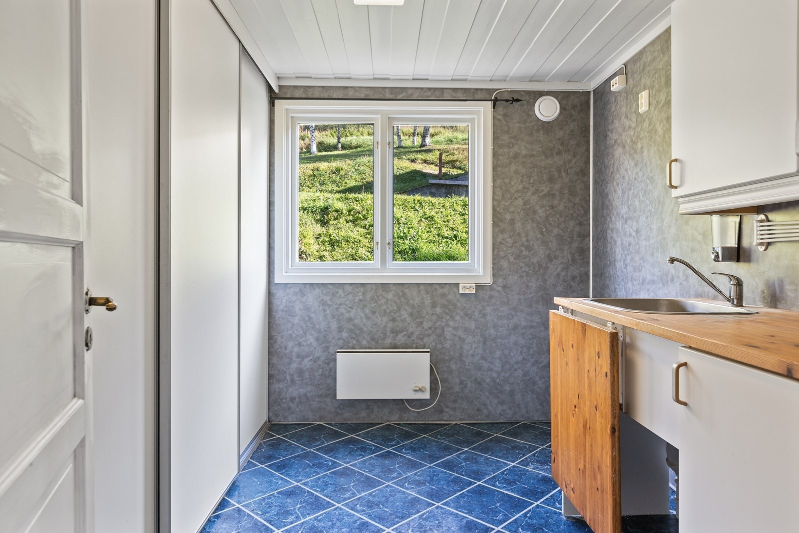 Et eget praktiske vaskerom med fliser på gulvet og baderomsplater på veggene. Galleribilde