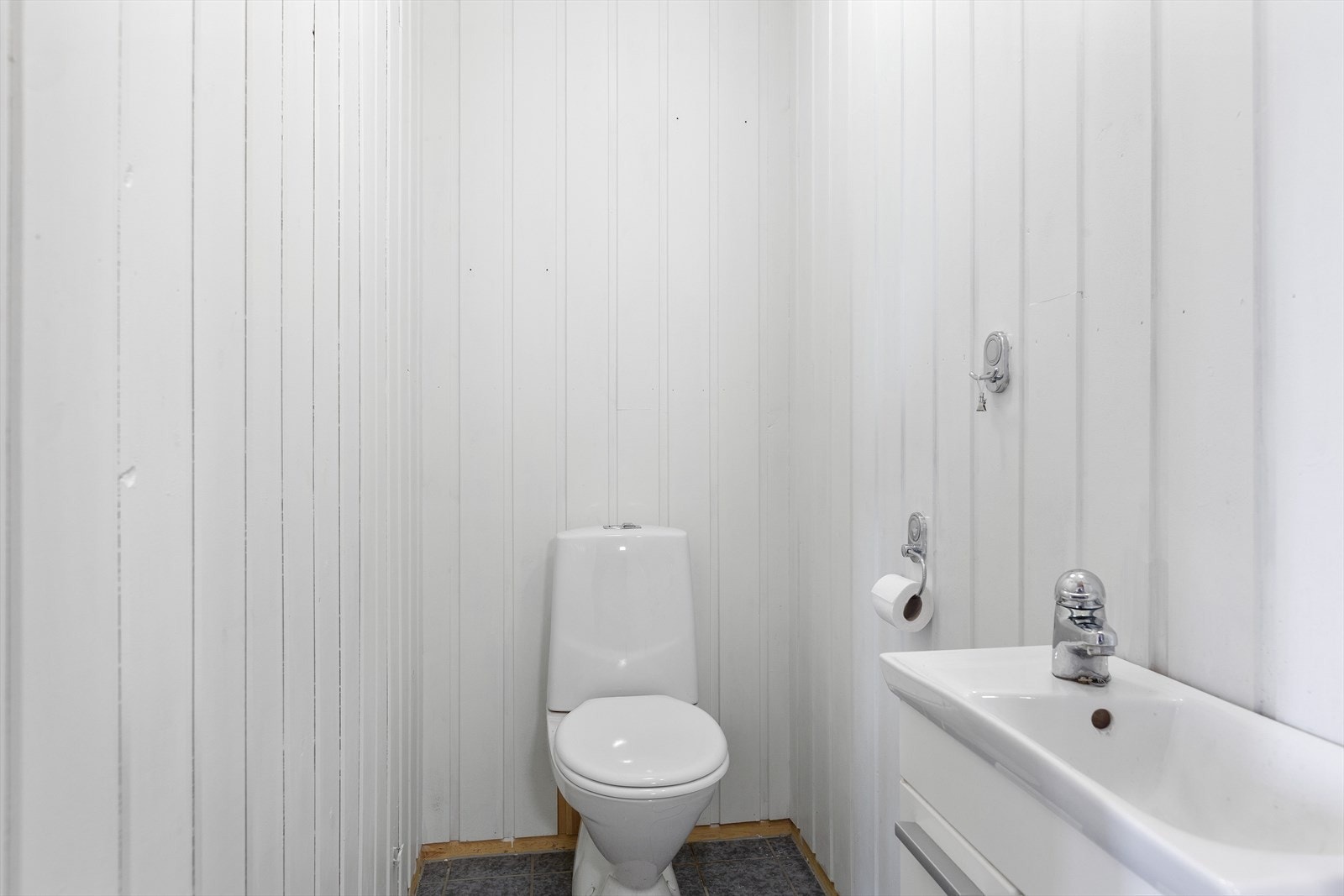 Ved siden av badet i .etasje, i våningshuset er et eget toalettrom med fliser på gulv og panel på veggene. Galleribilde