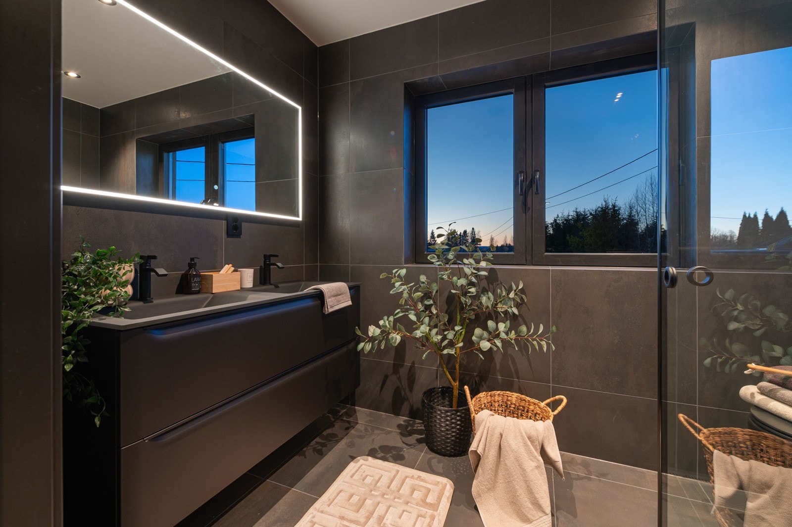 Smakfullt hovedbad i boligens 2. etasje tilknyttet boligens suite-avdeling. Badet har delikate storformatfliser på gulv- og veggflater i mørk utførelse. Himlingen er pent lyssatt med downlights. Galleribilde
