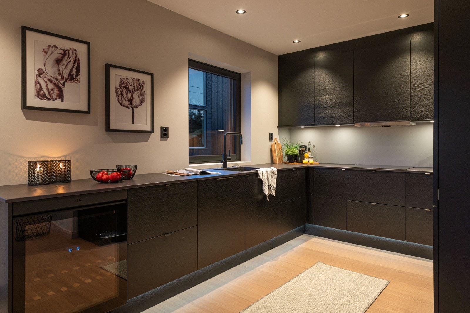 Innredning med mørke slette fronter av typen sort eik med foring opp til tak og lekker benkeplate i eksklusiv stein av typen Dekton Sirus i 2 cm tykkelse. Legg merke til det integrerte vinskapet! Galleribilde