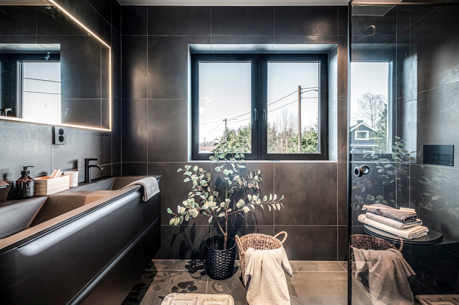 Videre har badet et separat dusjhjørne med innfellbare glassdører og regnfallsdusj av typen Azur. Det er påkostet armaturer og omramminger i sort design. Galleribilde