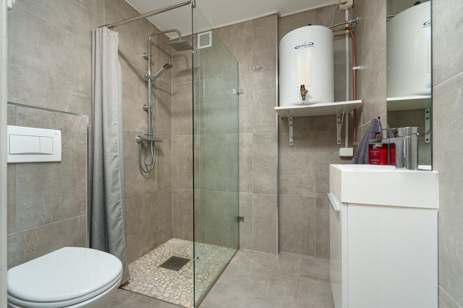 Pent helfliset bad/vaskerom. Her bys det på dusjhjørne, opplegg for vaskemaskin, veggmontert toalett og servant med møbel. Ingen varmekilde. Naturlig ventilering. Galleribilde