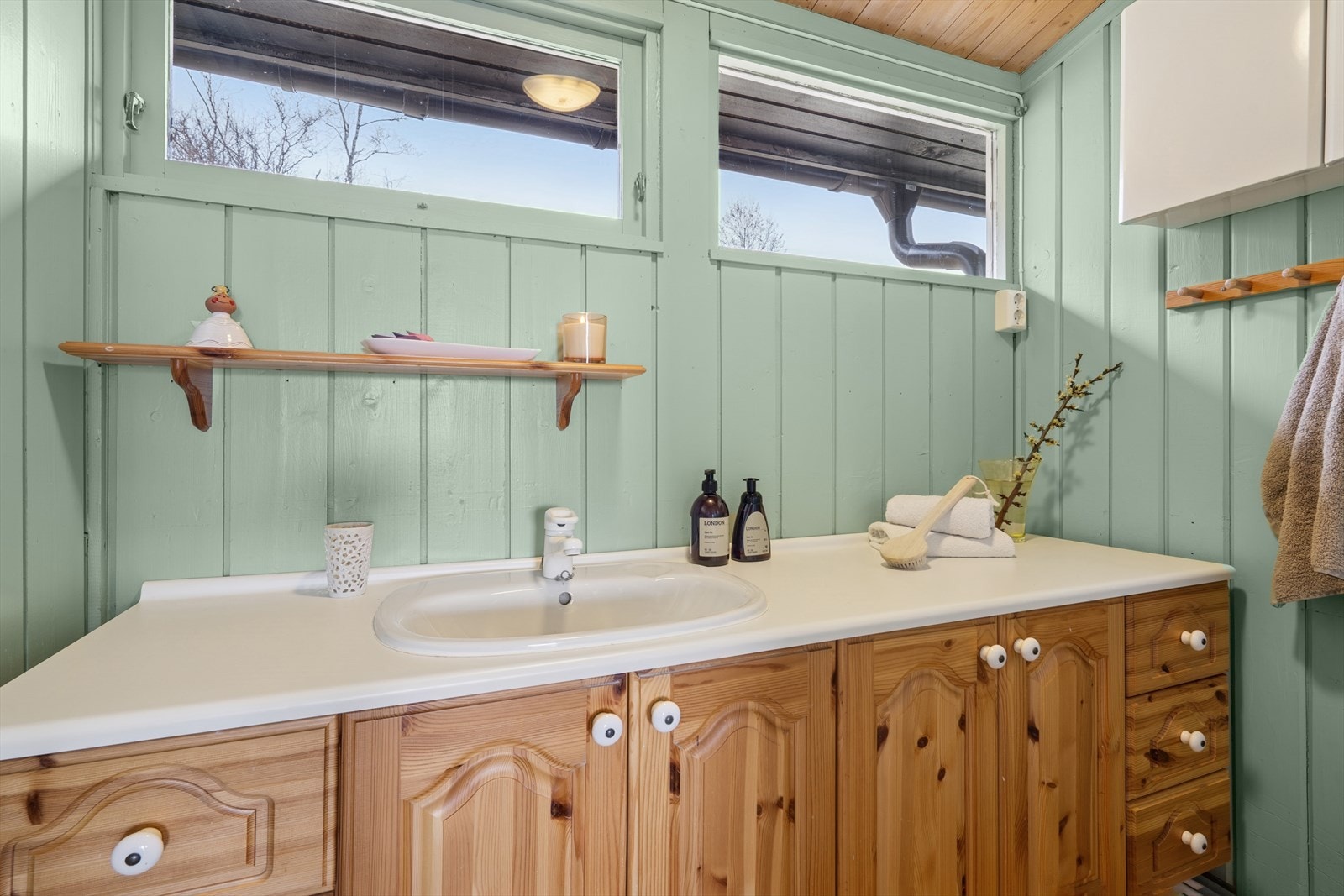 Baderommet er innredet med dusjkabinett og servant med skap og skuffer under. Galleribilde