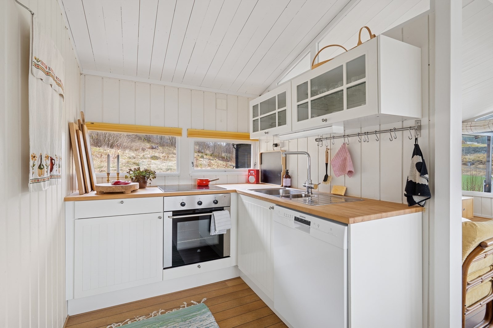 Tidløst innredet kjøkken med hvite fronter og benkeplate i heltre. Galleribilde