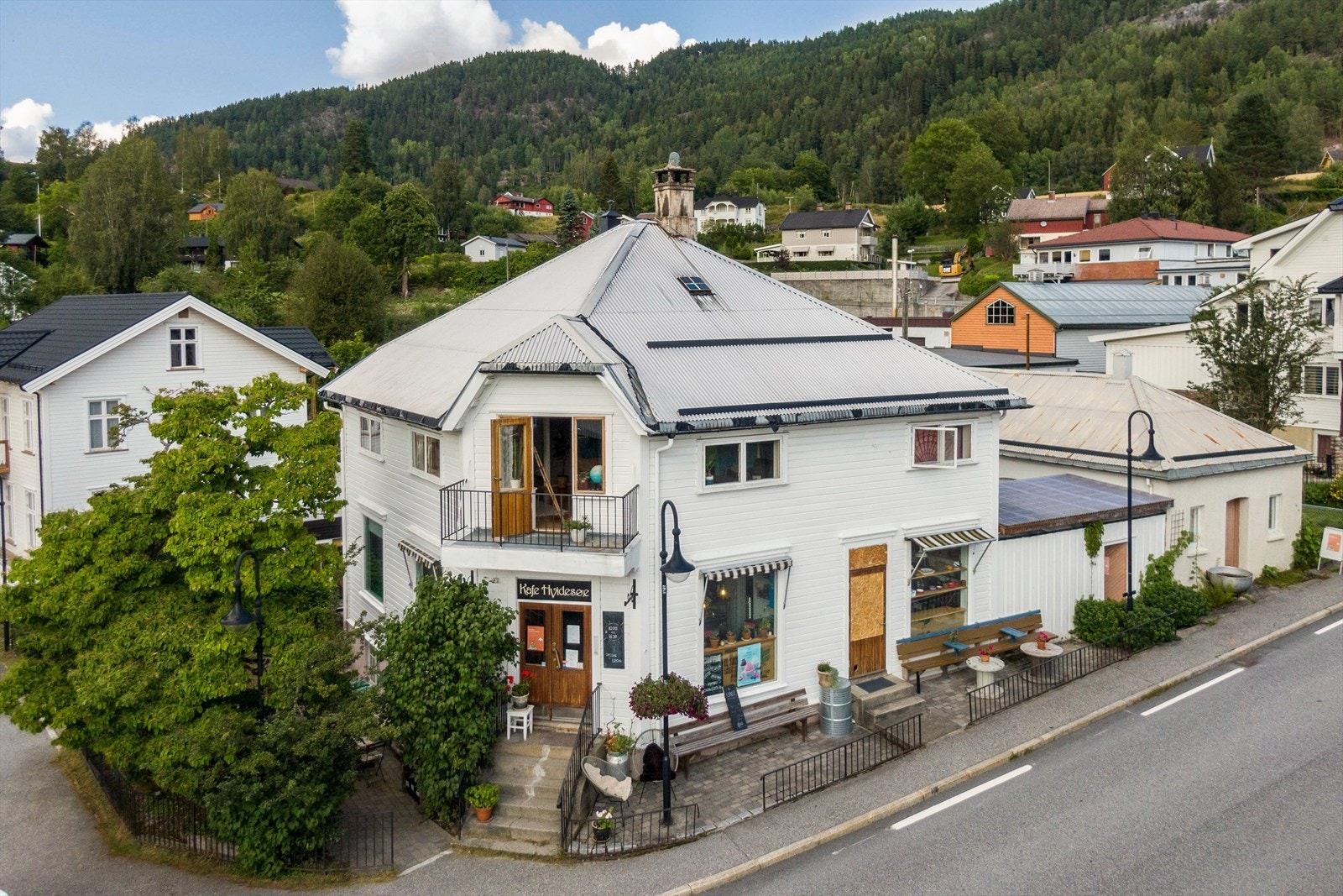 Hjørneplassering, smijernsgjerder og brostein gir en umiddelbar tilstedeværelse, og inviterer forbipasserende inn. Galleribilde