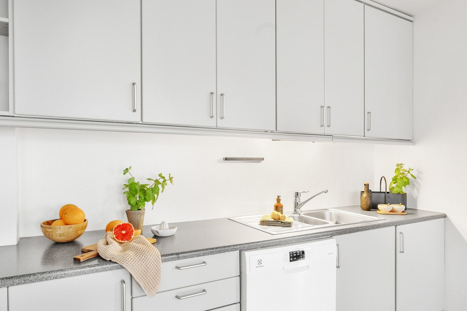 Det er videre innredet med frittstående komfyr, oppvaskmaskin og kjøleskap med fryser. Benkeplaten er av laminat, og over er det benkeskapbelysning og stikkontakter. Galleribilde