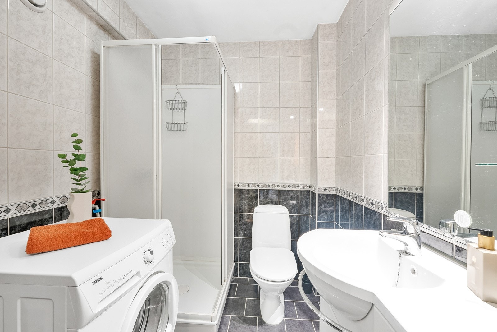 Baderommet har flislagte vegger og gulv, og er innredet med vegghengt servantinnredning med dører, dusjkabinett, gulvstående toalett, opplegg for vaskemaskin og varmekabler. Galleribilde