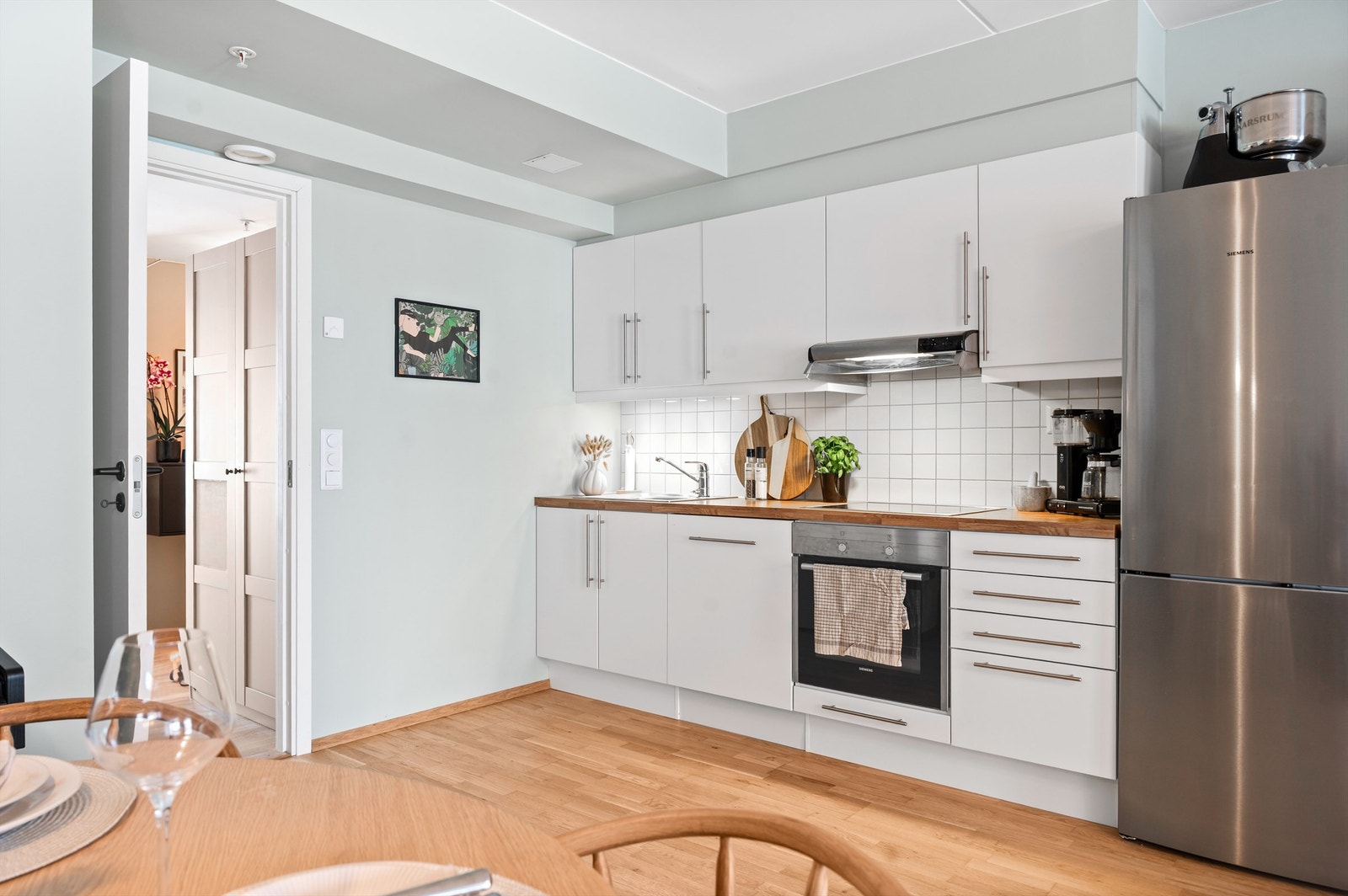 Det er montert benkeskapsbelysning og stikkontakter over kjøkkenbenk samt delikate fliser på vegg over benkeplaten. Galleribilde