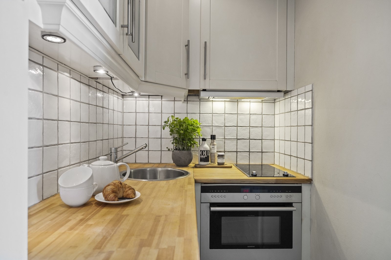 Det er montert en nedfelt kum i rustfritt stål, samt integrerte hvitevarer som platetopp og stekeovn. Over innredningen er det mekanisk avtrekk Galleribilde