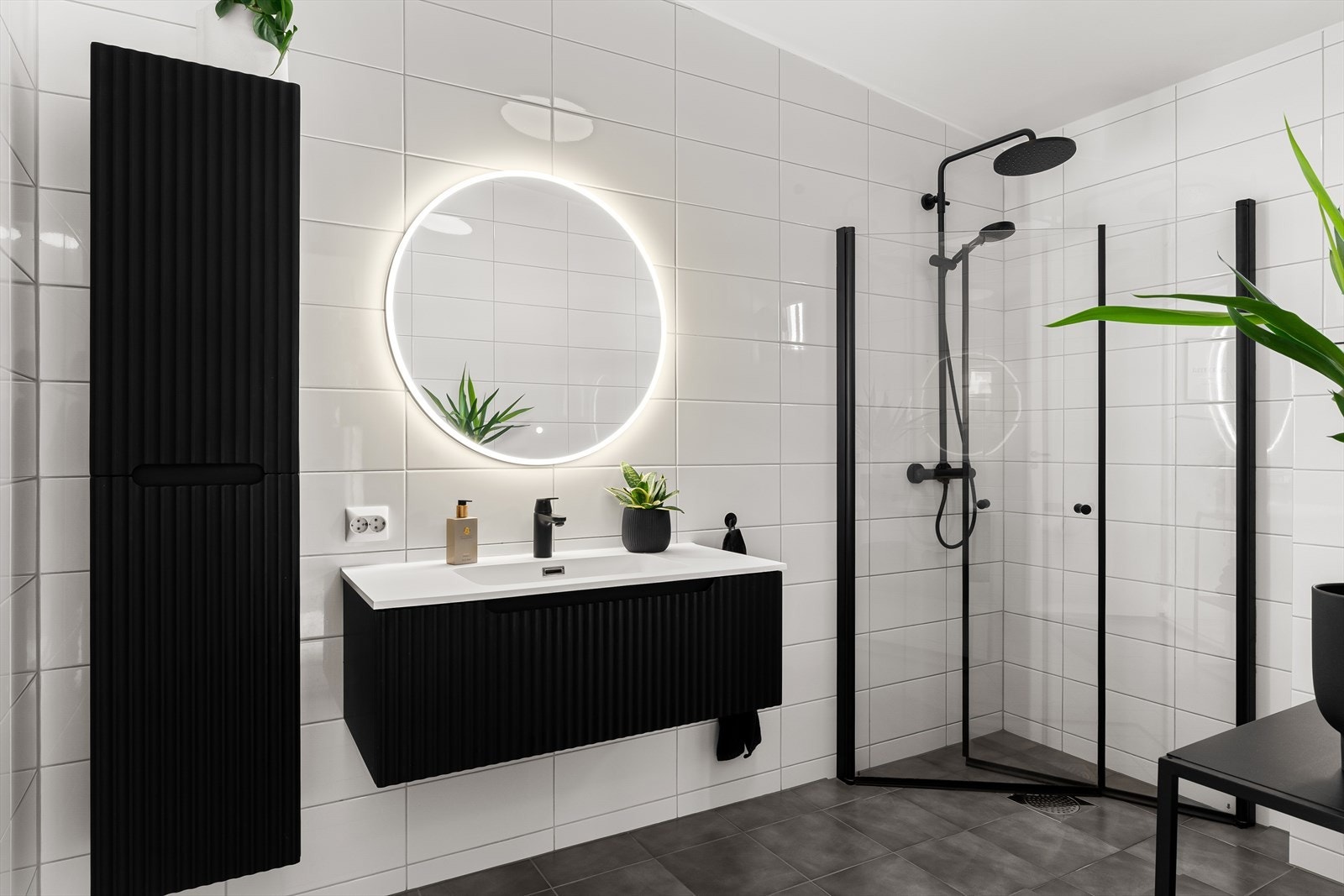 Stilfullt bad med flislagte gulv og vegger, nyere innredning og elegant dusj i sort. Galleribilde