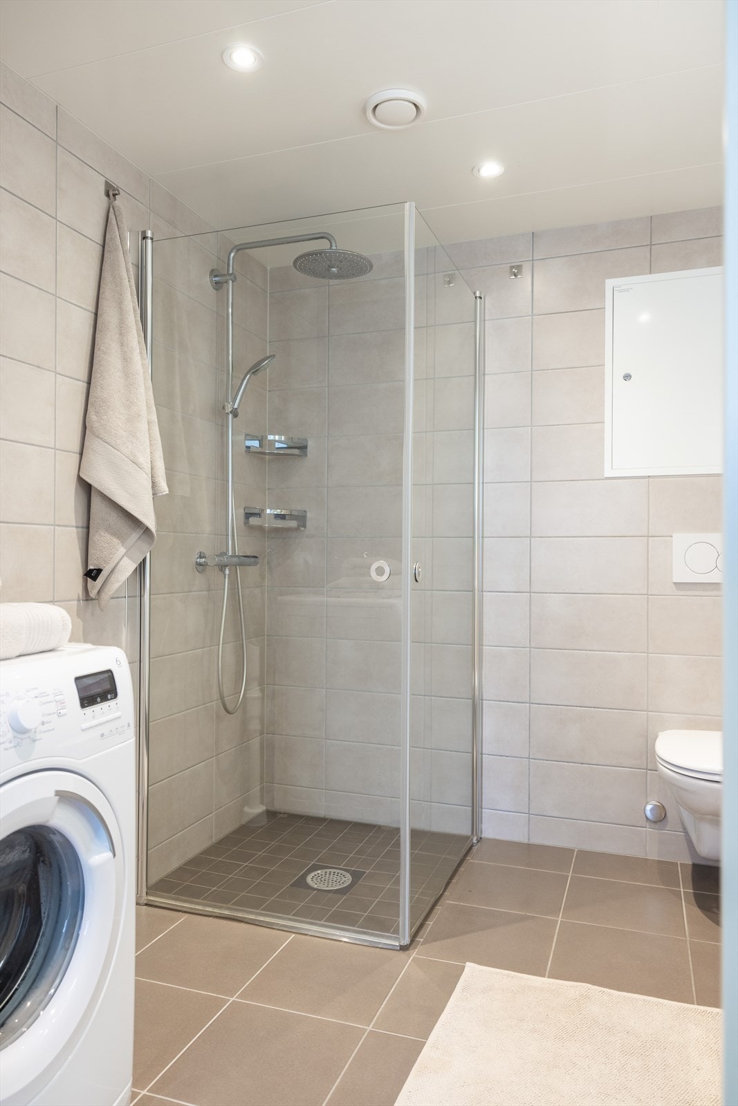 Badet er innredet med vegghengt klosett, servant med innredning, speil m/lys og dusjhjørne med svingbare glassdører. Galleribilde
