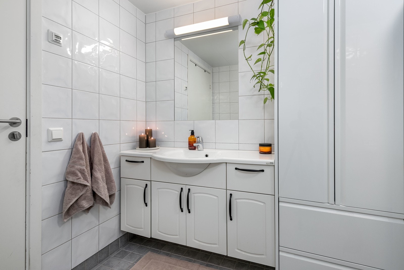 Innredningen består av benkeskap og høyskap med innfliset speil over servant. Toalettet er vegghengt, og dusjhjørnet har innfellbare dører i herdet glass. Galleribilde