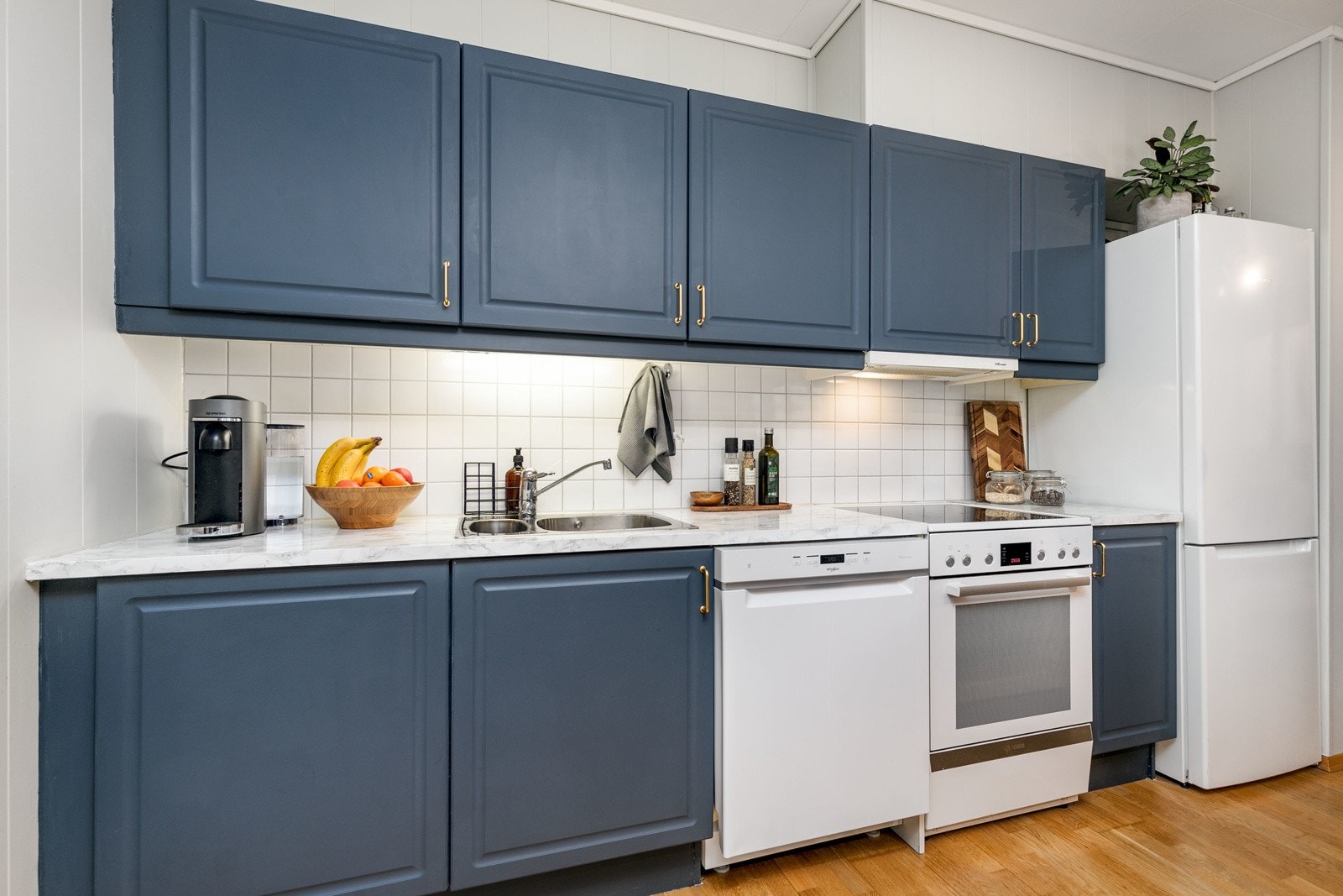 Kjøkkeninnredningen består av mørke profilerte fronter med belysning under overskap og fliser på vegg over benkeskap. Galleribilde