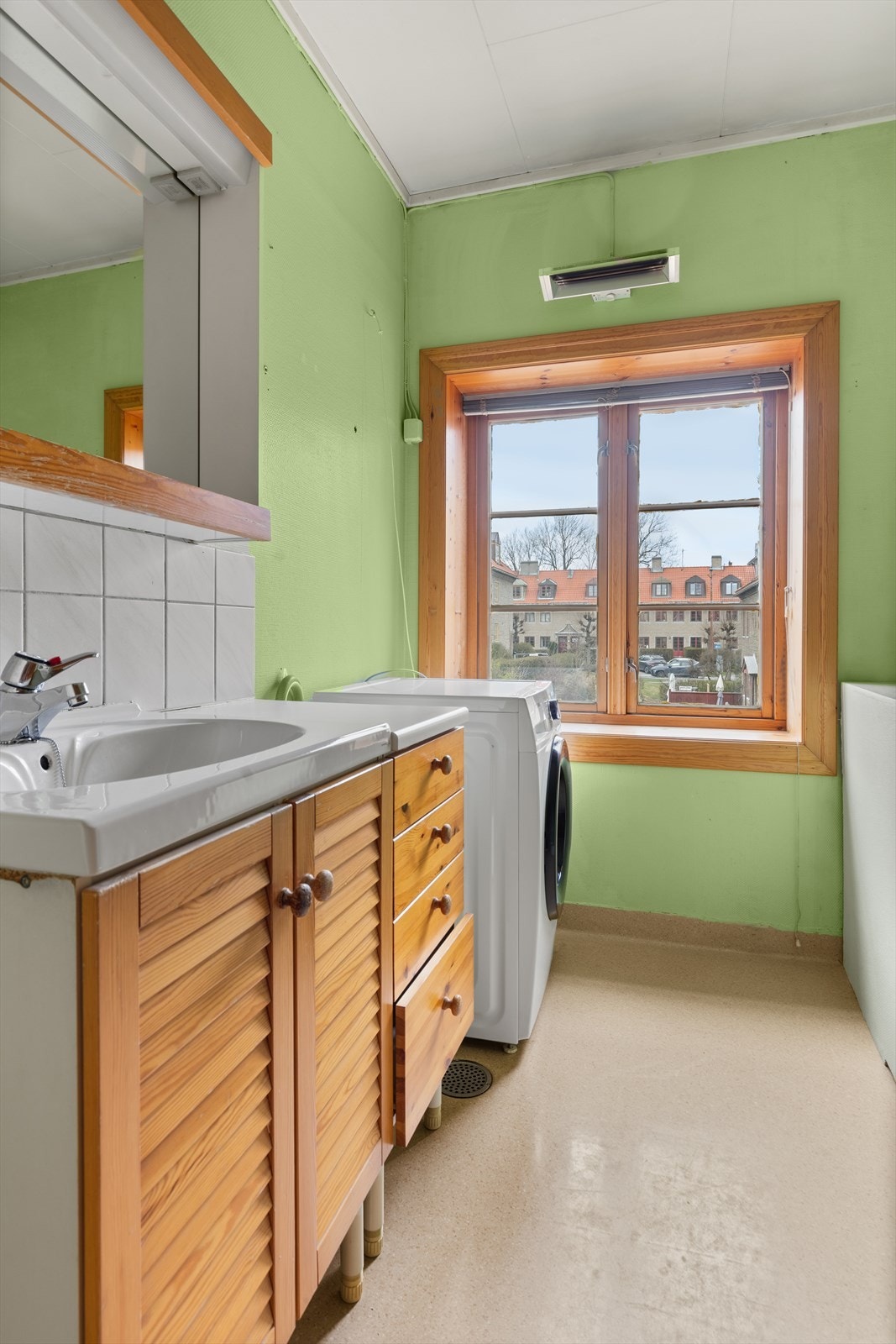 Elektrisk varmelampe på vegg. Gulvstående servantinnredning med laminert benkeplate og overliggende servant med ett-greps armatur. Skap for oppbevaring. Galleribilde