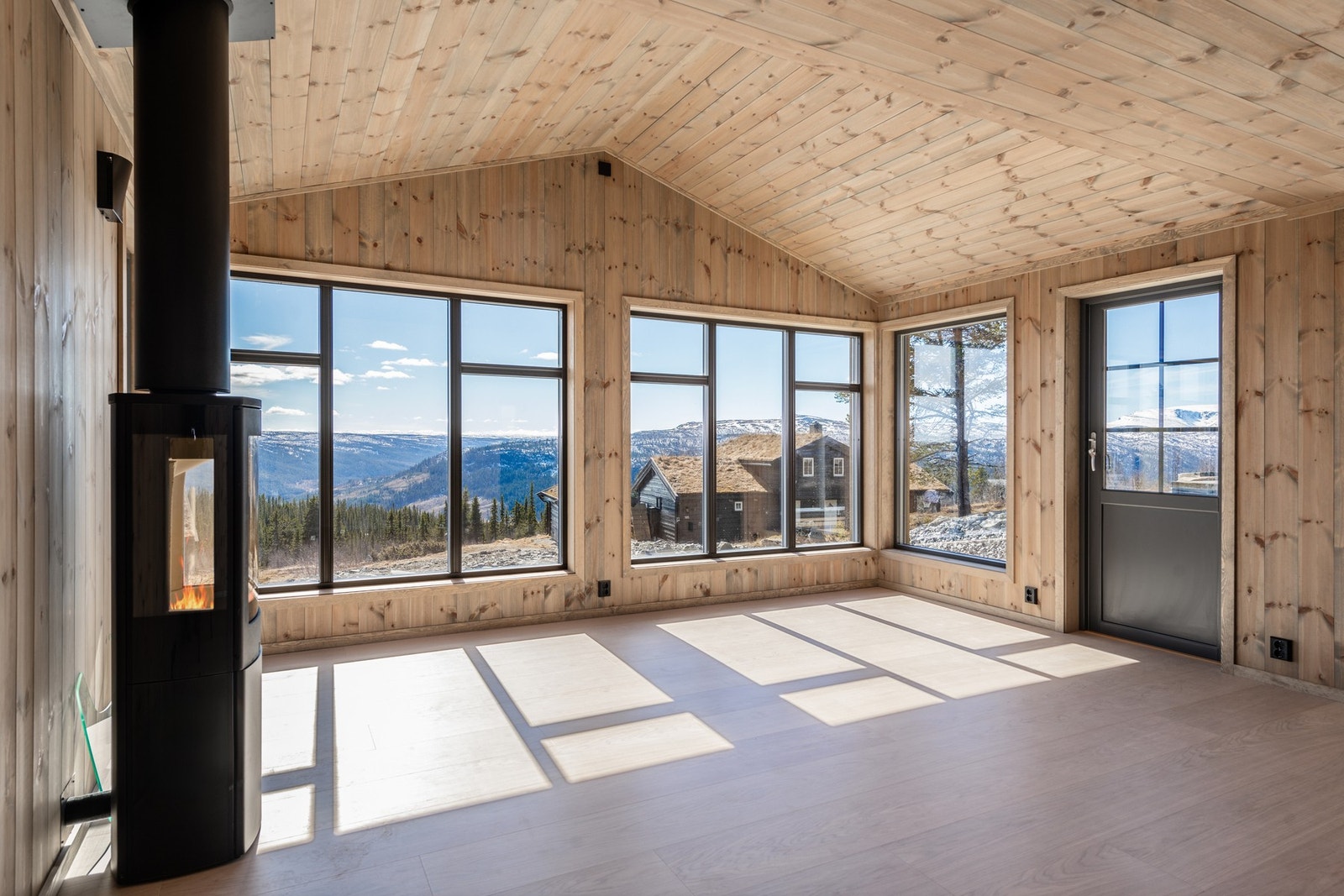 Stuen er åpen med god takhøyde, og store vinduer som slipper både lyset og naturen inn Galleribilde