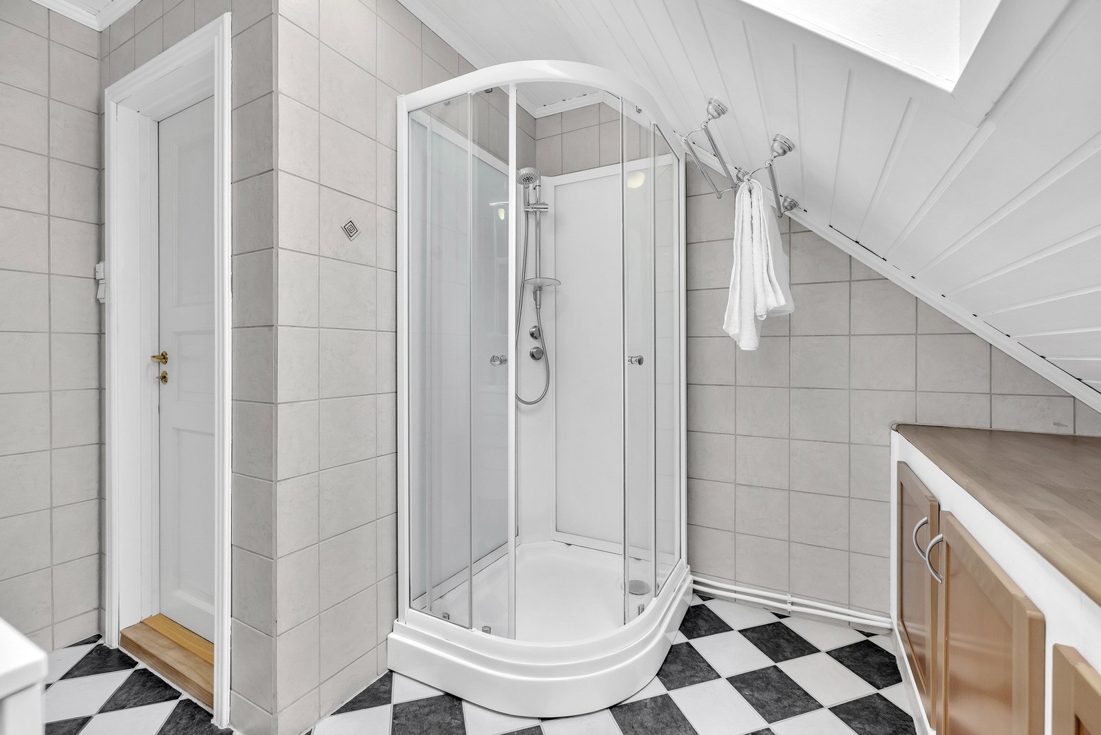 Badet inneholder vegghengt servantskap, servant, gulvmontert toalett og dusjkabinett. Galleribilde