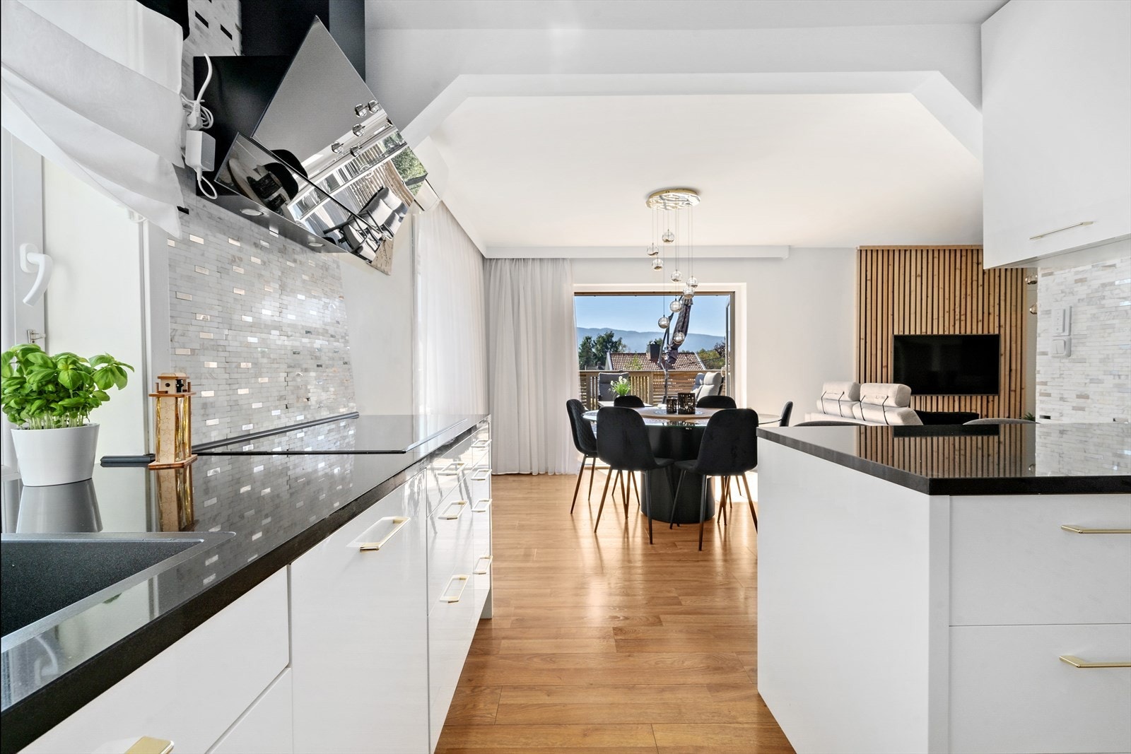 Kjøkkenet har hvite glatte fronter. Det er benkeplate i stein/granitt og mosaikkfliser over benk. Galleribilde