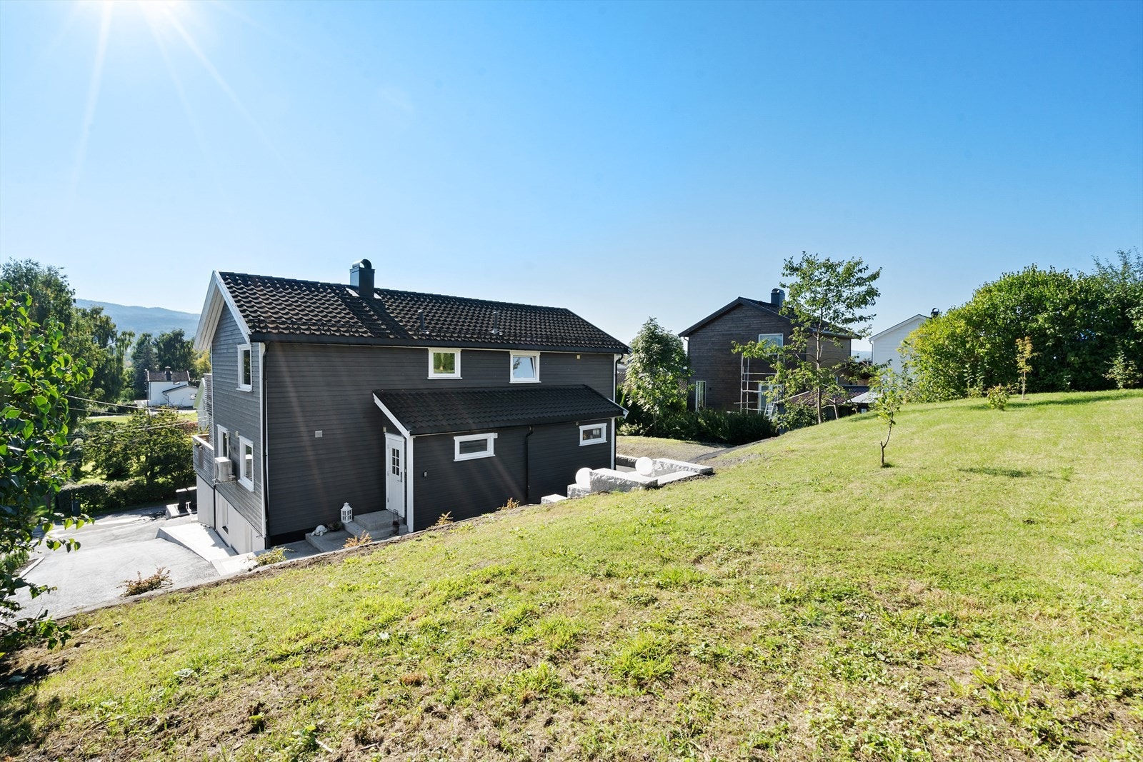 Gresslagte områder med mindre bærbusker. Eiendommen er avgrenset med hekk. Uteområdene er nylig påkostet betydelige midler og det er anlagt flere platåer samt bark og beplantet. Galleribilde