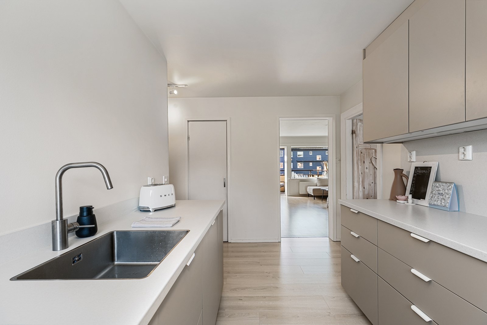 Innredningen består av slette fronter i beige farge, laminat benkeplate og belysning under overskap. Galleribilde