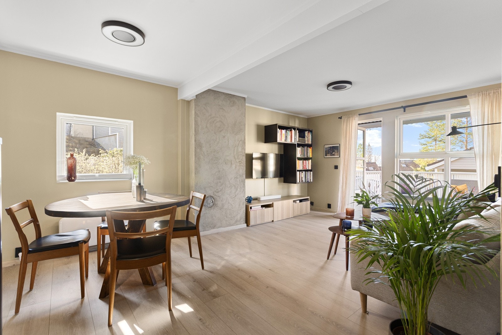 Stua er et lyst og trivelig rom med spiseplass, bokhyller og store vinduer som gir godt med naturlig lys Galleribilde