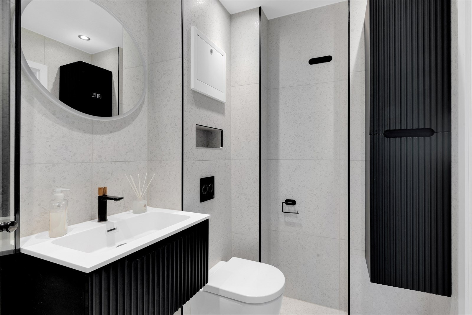 Innredningen består av hengslede dusjvegger, servant med underskuffer, speil med integrert lys, veggskap, vegghengt wc, opplegg for vaskemaskin og varmekabler i gulv. Galleribilde