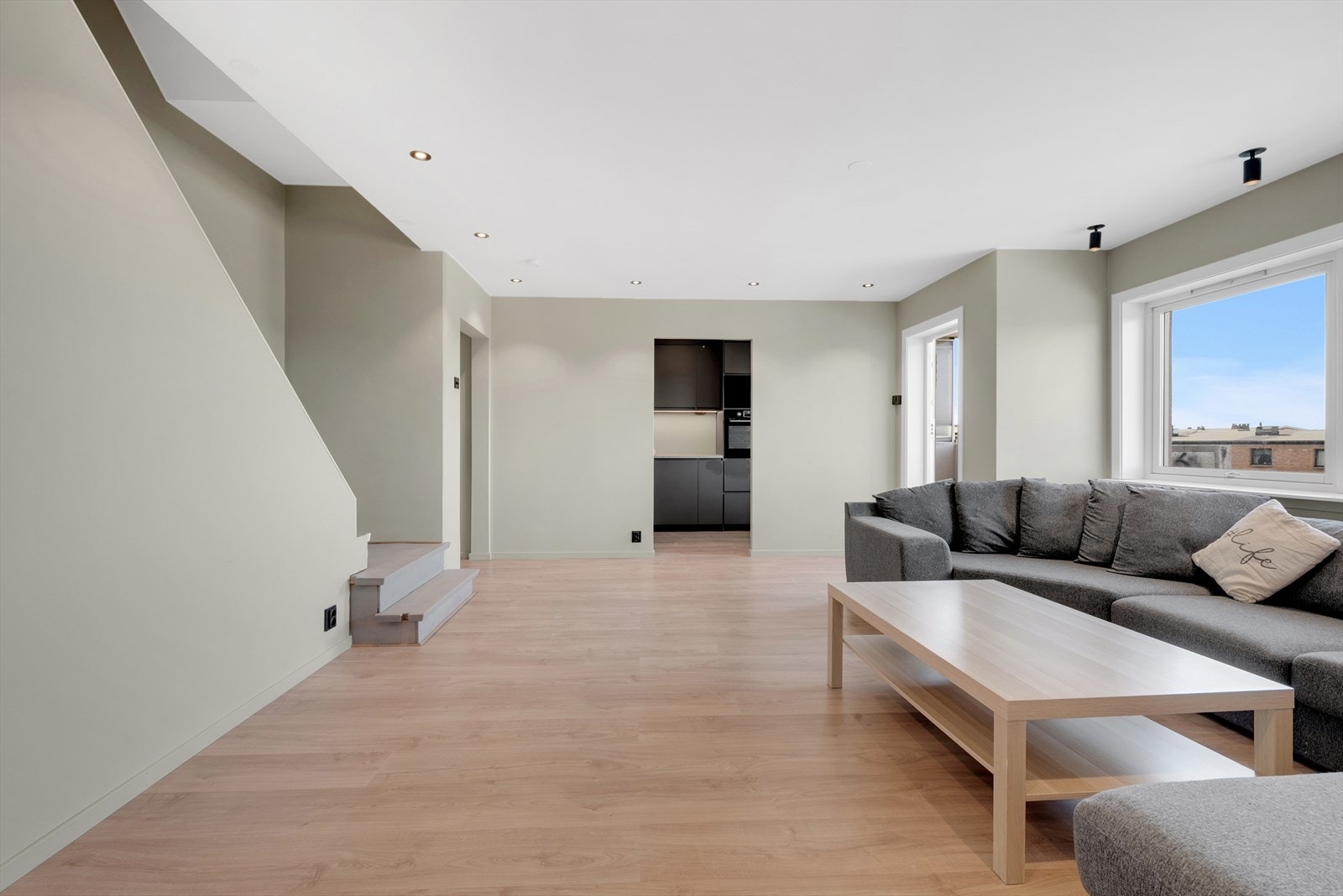 Romslig stue med laminat på gulv, malte slette vegger og malt tak med downlights. Fra stuen er det utgang til en hyggelig vestvendt balkong på 5 kvm med god utsikt. Galleribilde