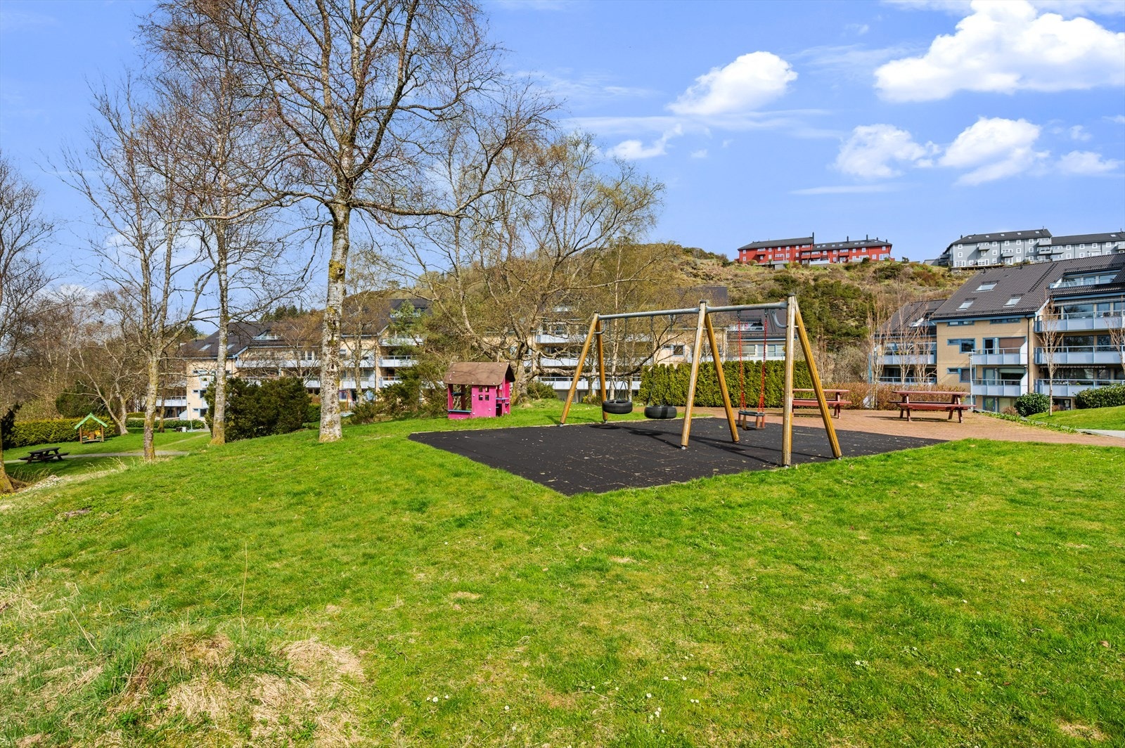 Tomten er pent opparbeidet med grøntområder, benker, bord og lekeapparater. Galleribilde