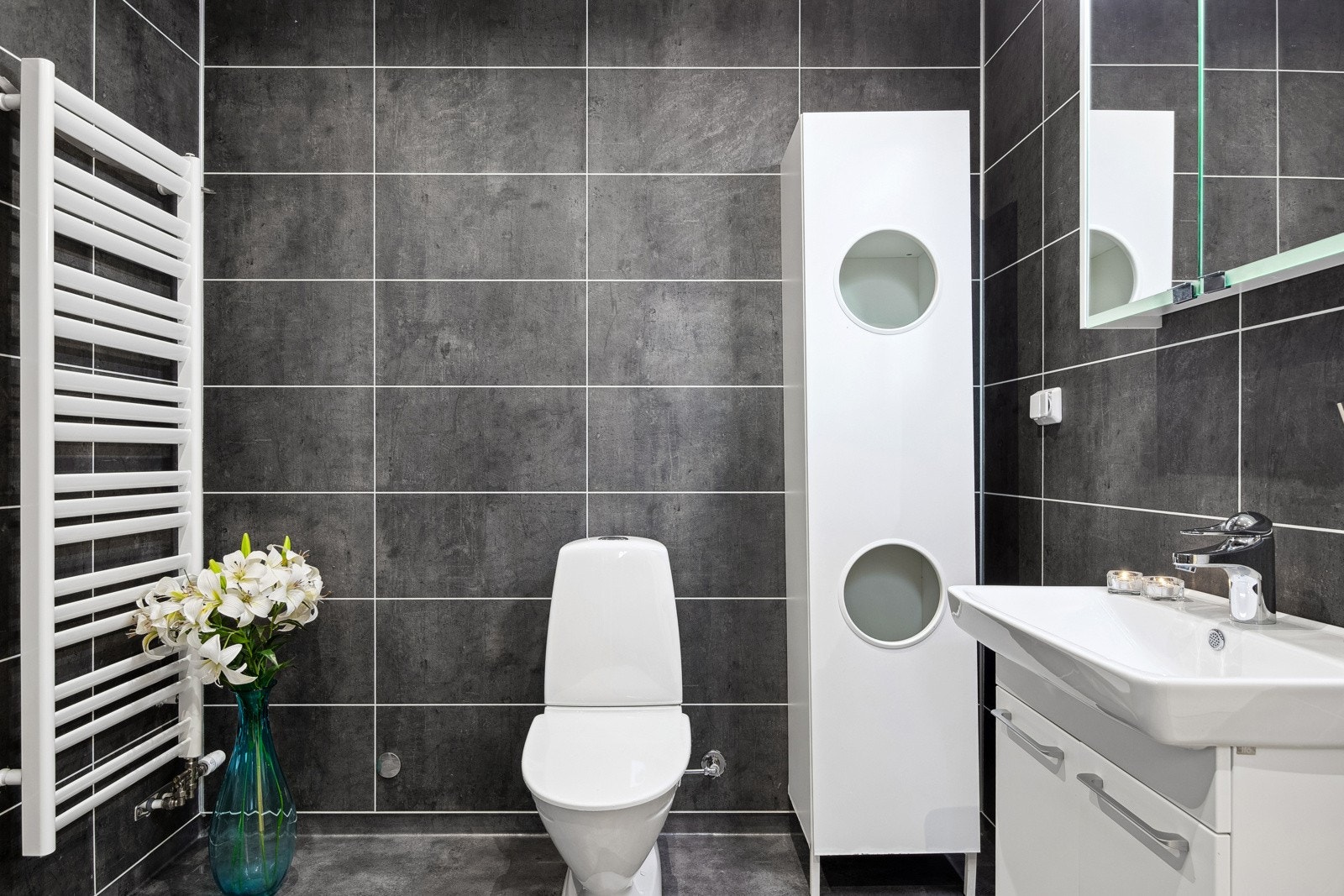 Badene er velutstyrt med dusjhjørne, toalett, vegghengt servant og overskap med speilfronter. Galleribilde