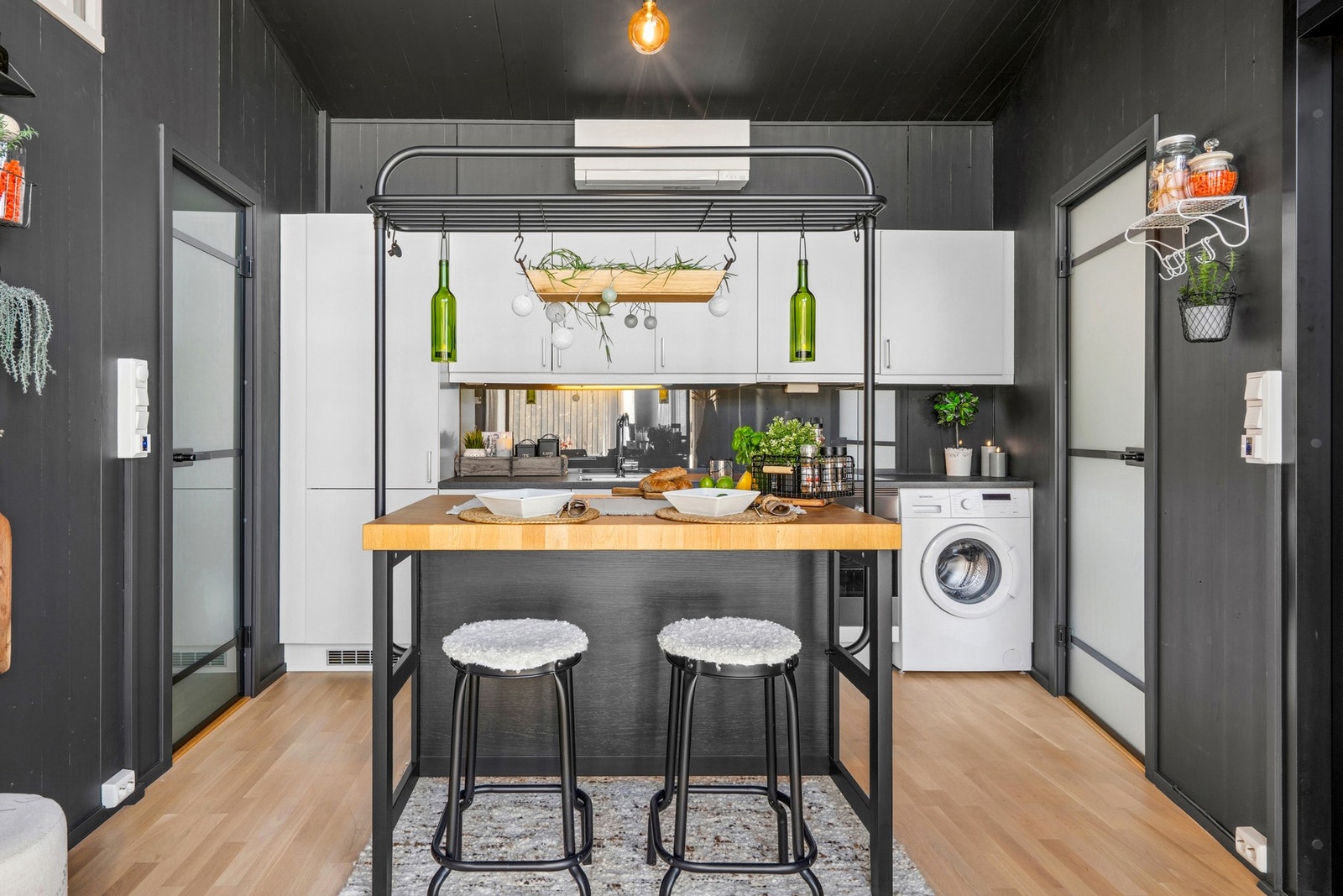 Flott og lyst kjøkken fra HTH ssom ligger i åpen løsning mot stuen. Vaskemaskinen er plassert helt til høyre under kjøkkenbenken Galleribilde