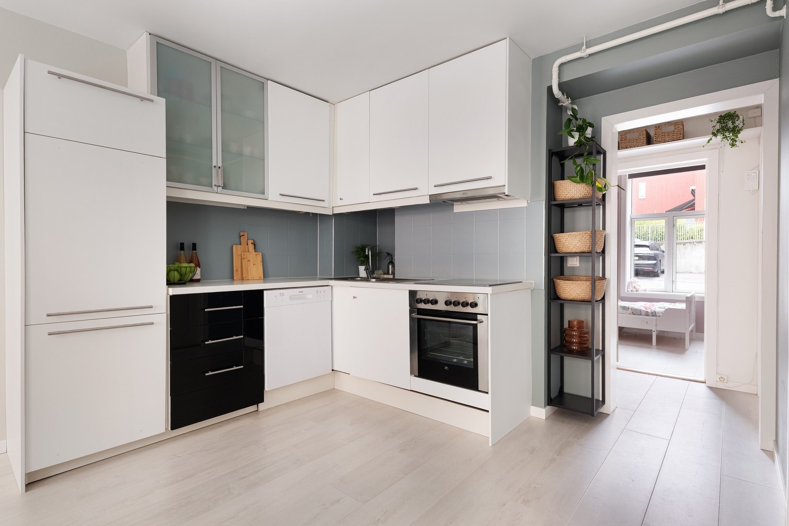 Lys, glatt innredning med høyglans fronter, to fronter med glassfelt, laminat benkeplate og nedsenket oppvaskkum med ett-greps armatur. Galleribilde