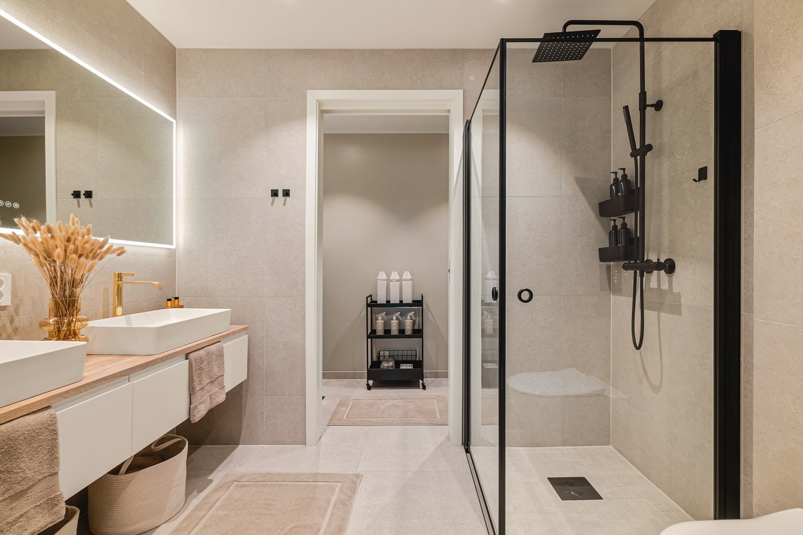 De sorte detaljene som flott kontrast til de lyse flisene | Det bakbelyste speilet i kombinasjon med dobbelt servant gir et eksklusivt preg Galleribilde