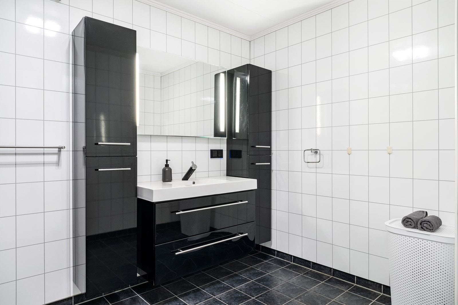 Badet er oppgradert med flis på golv og baderomsplater med flismønster på veggar. I taket er det kvite plater. Galleribilde