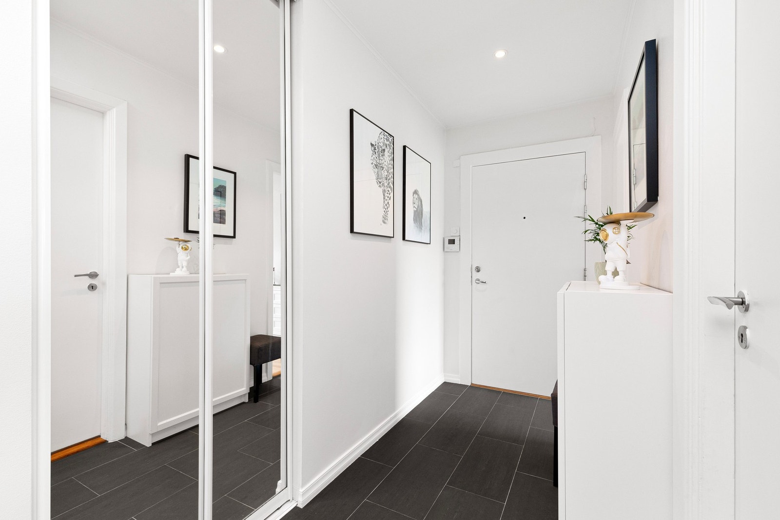 Lys og innbydende entré med innfelt garderobe i helspeil og flislagt gulv. Galleribilde