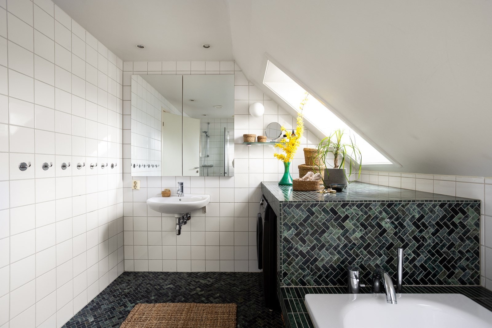 Badet er utstyrt med vegghengt wc, servant, dusj i hjørne med innadslående dører og innmurt badekar. Galleribilde