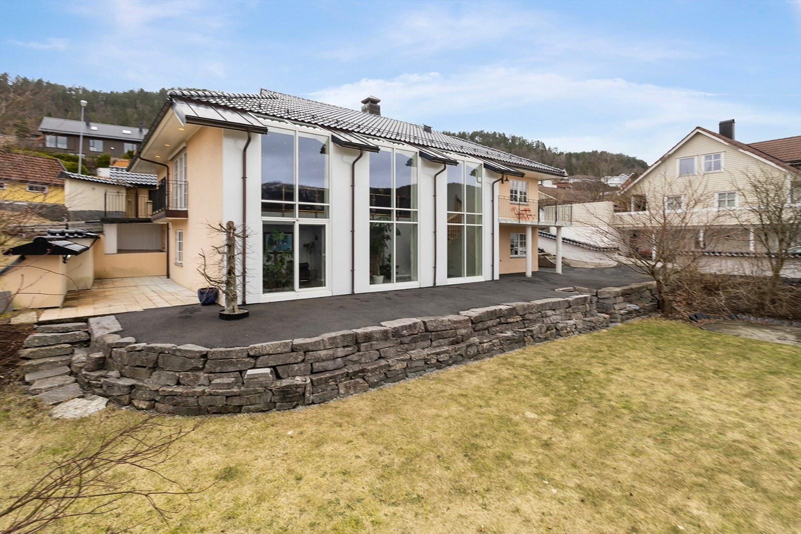 Uteplassen er omkranset av plen og hage med beplantning. Galleribilde