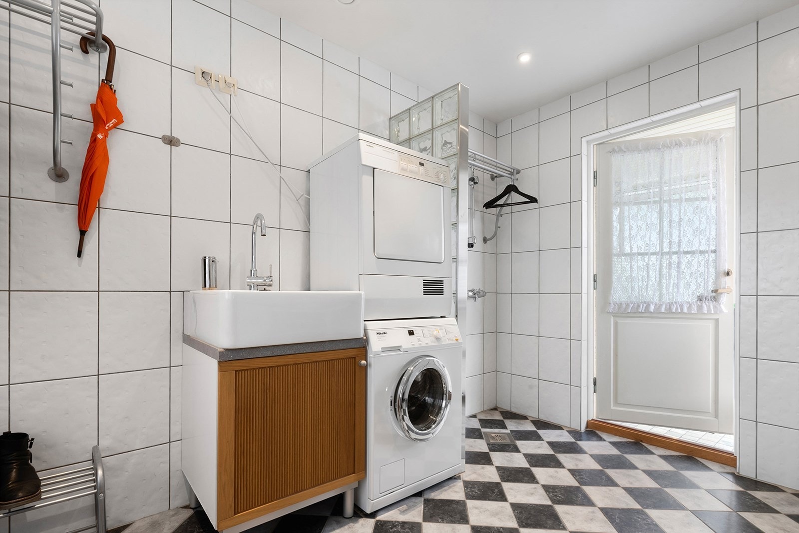 Vaskerommet har utgang til nordvendt uteplass som er delvis overbygd. Her er det god tørkeplass for klær og gjennomgang til garasjen. Galleribilde