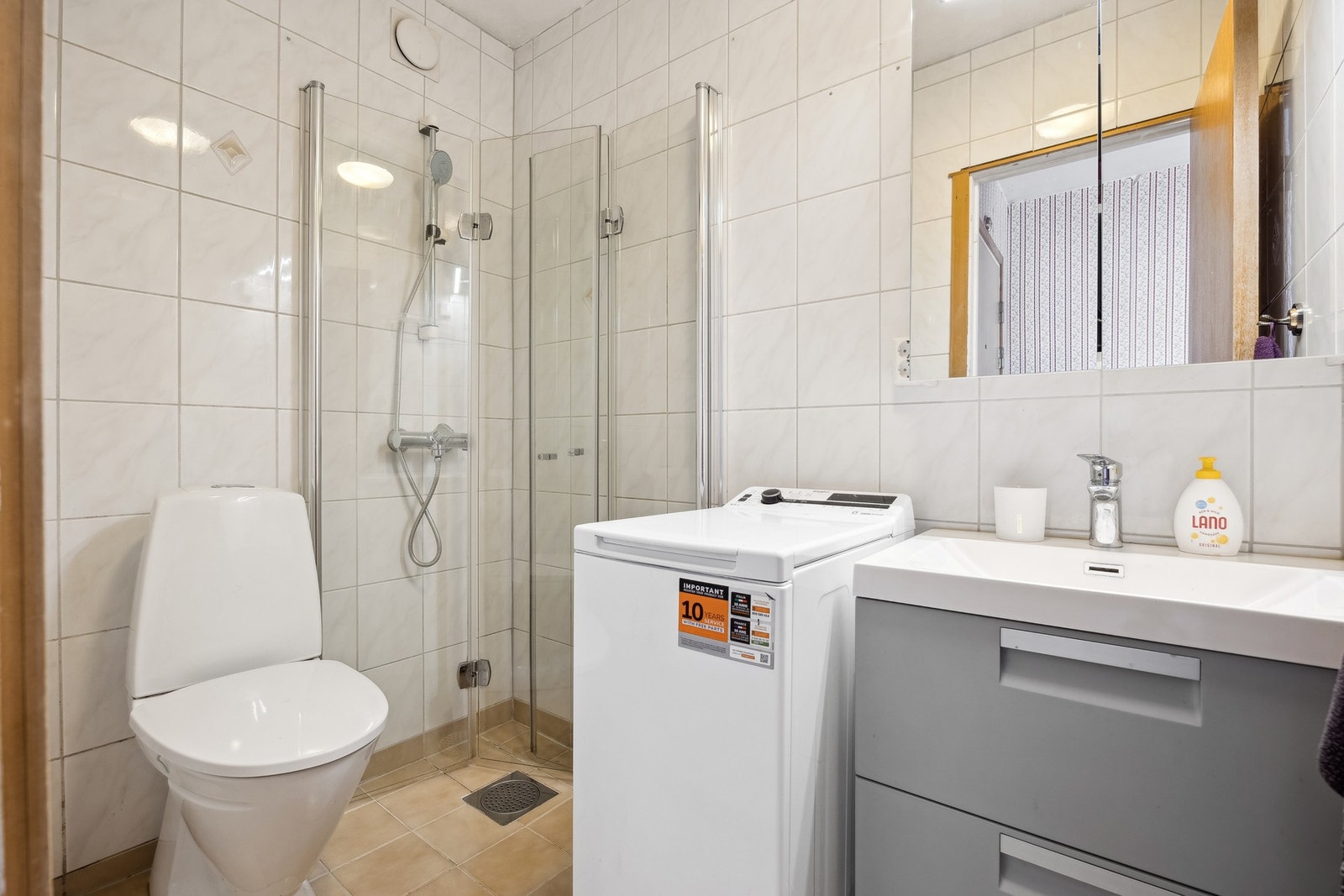 Bad med innfellbare dusjdører, servant og vegghengt speilskap. Galleribilde