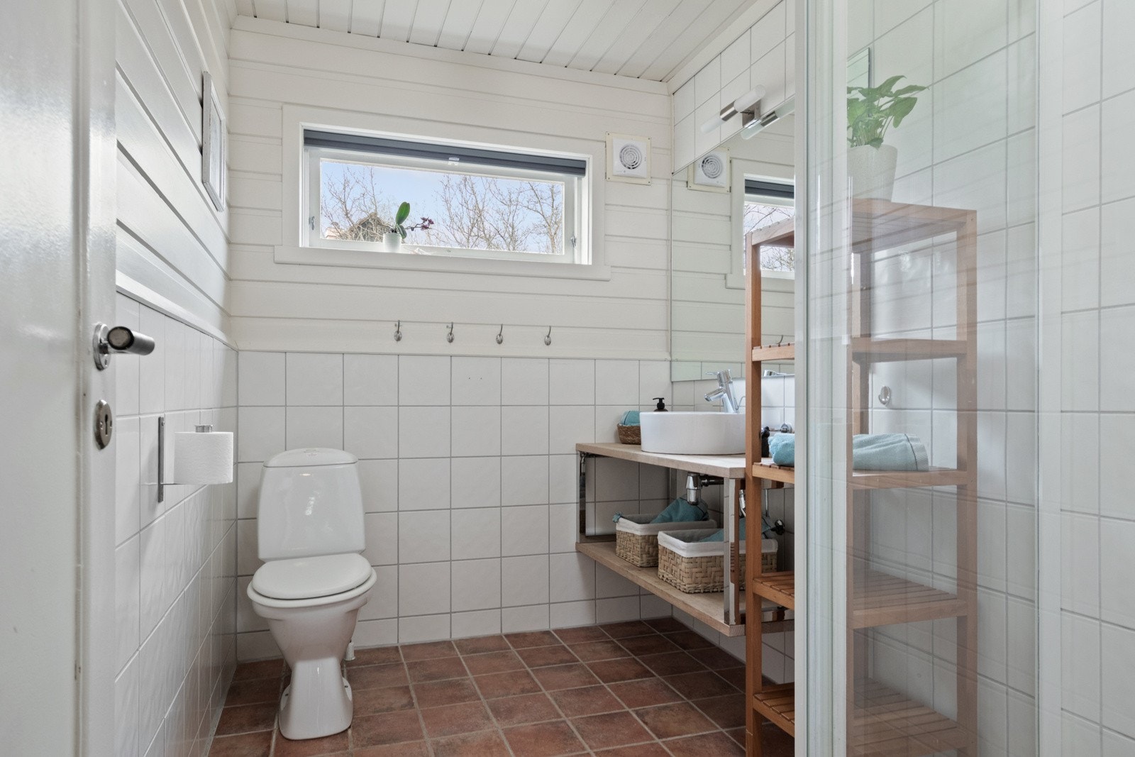 Badet nede har flislagt gulv med varme, mens veggene er kledd med fliser og malt panel i hvitt. Galleribilde