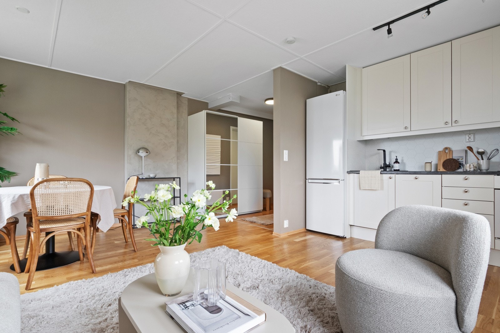 Over benken er det hvite plater med heksagonmønster, og over kokesonen har kjøkkenet en ventilator og en komfyrvakt. Galleribilde