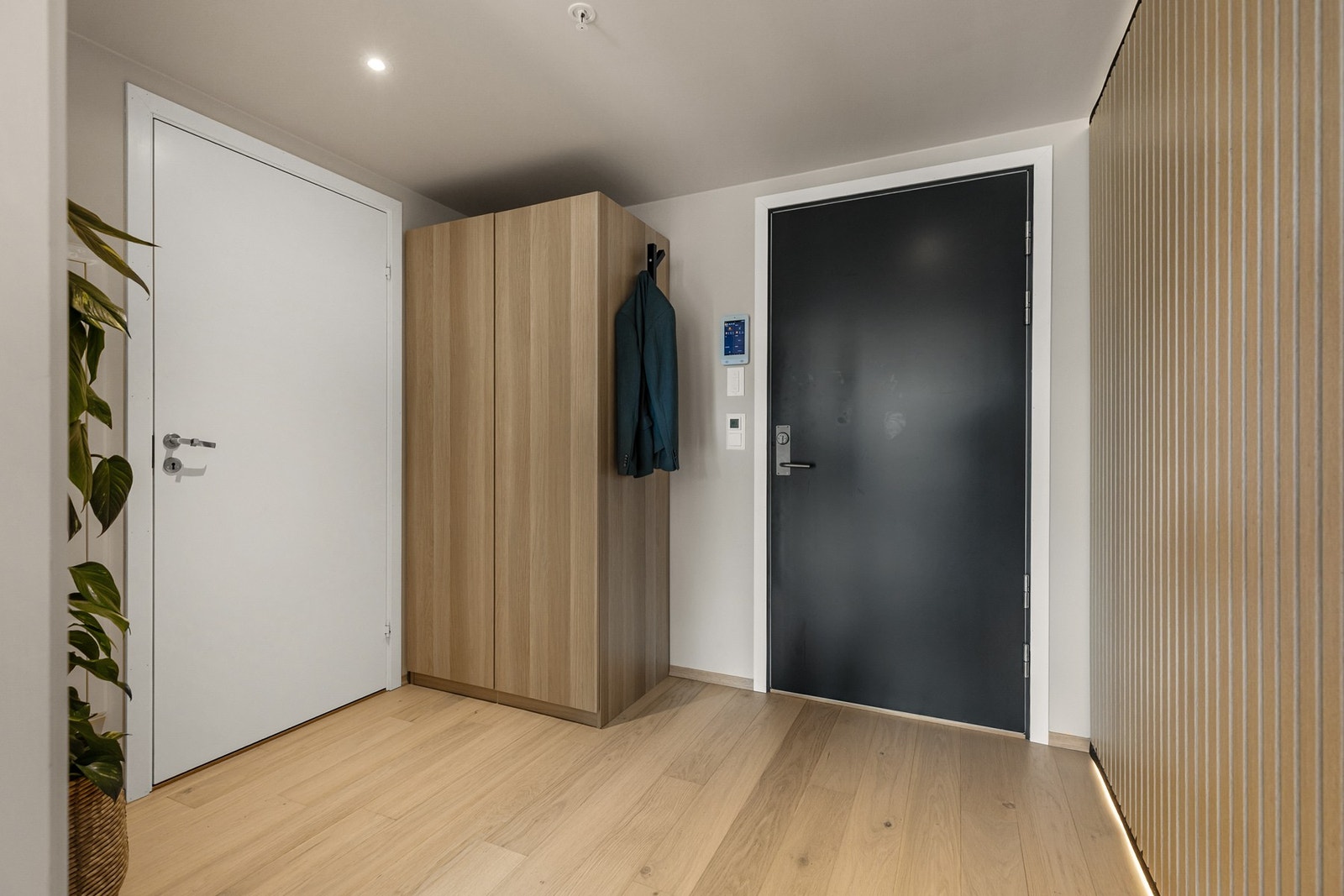 Romslig entré med enstavs parkett og en moderne spilevegg med integrerte lysstriper Galleribilde