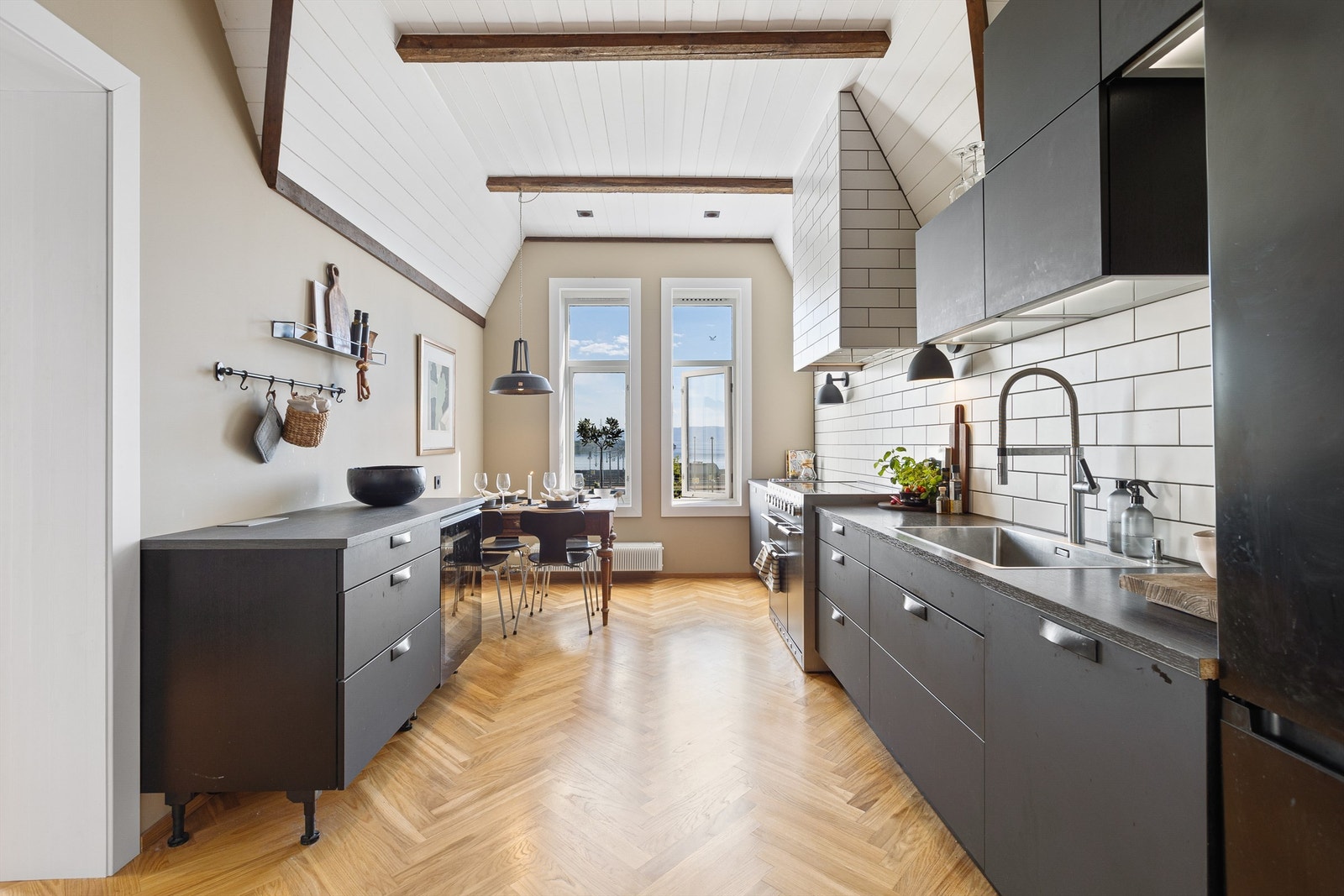 Stort kjøkken med stilig HTH innredning fra 2019 av glatte fronter og benkeplate av laminat med nedfelt oppvaskkum. Galleribilde