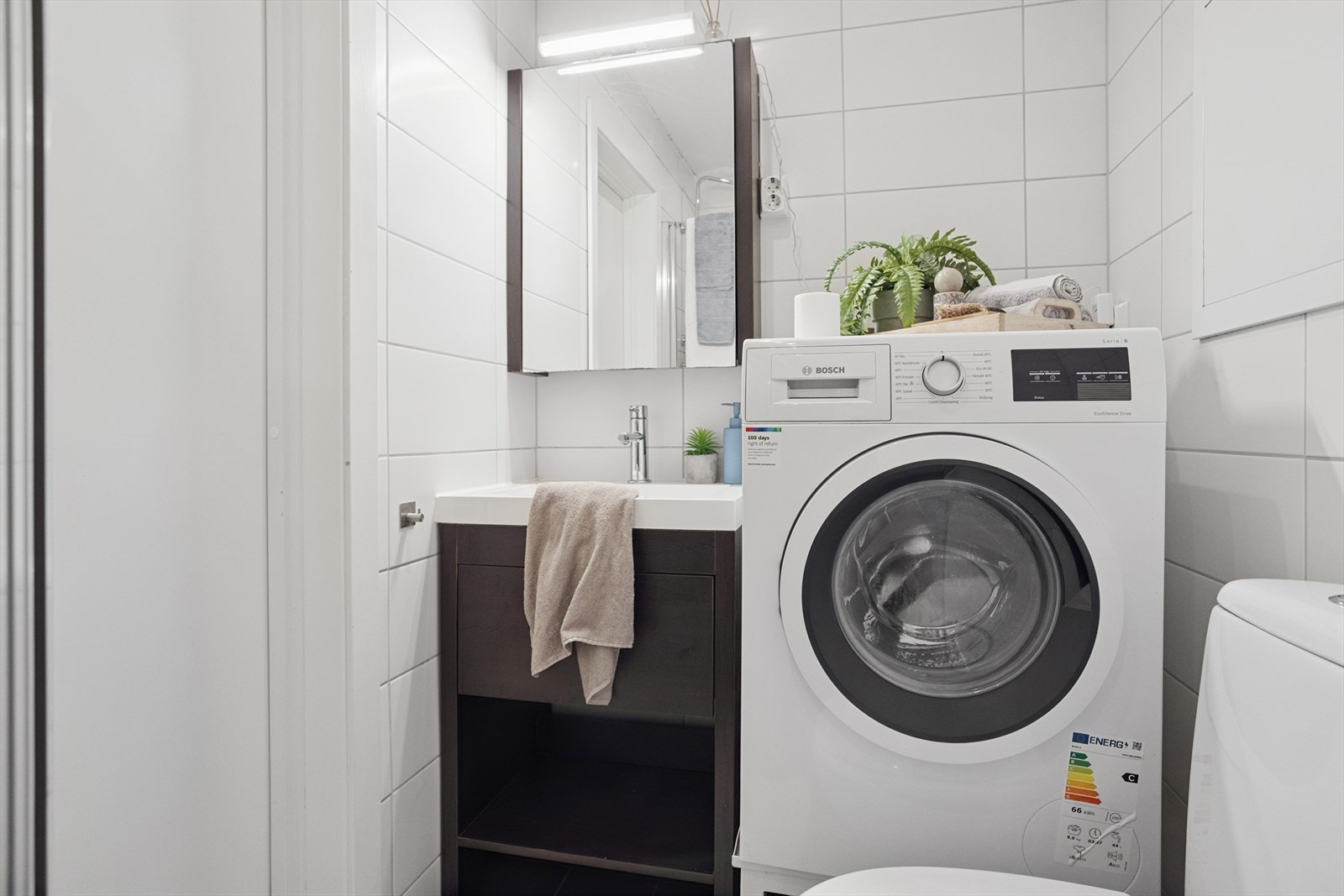 Baderommet har dusjvegger av glass, gulvmontert toalett, innredning med servant samt opplegg for vaskemaskin. Galleribilde