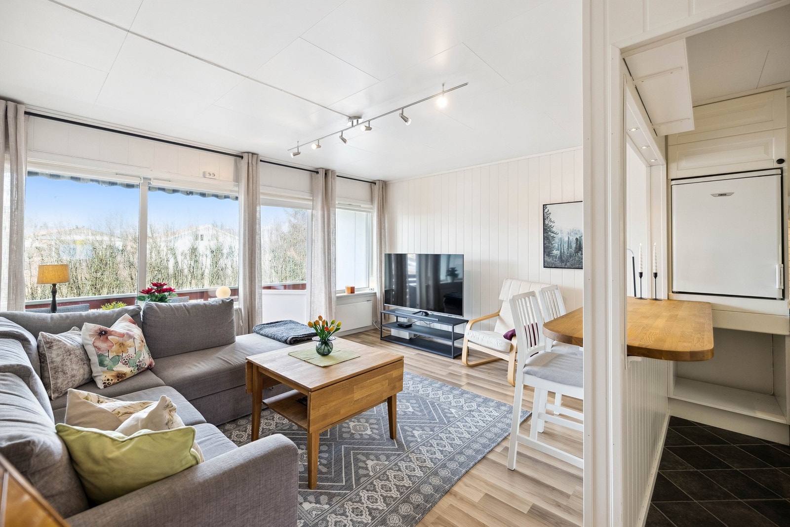 Koselig og lys stue med delvis åpen kjøkkenløsning. En praktisk barløsning binder rommene fint sammen Galleribilde