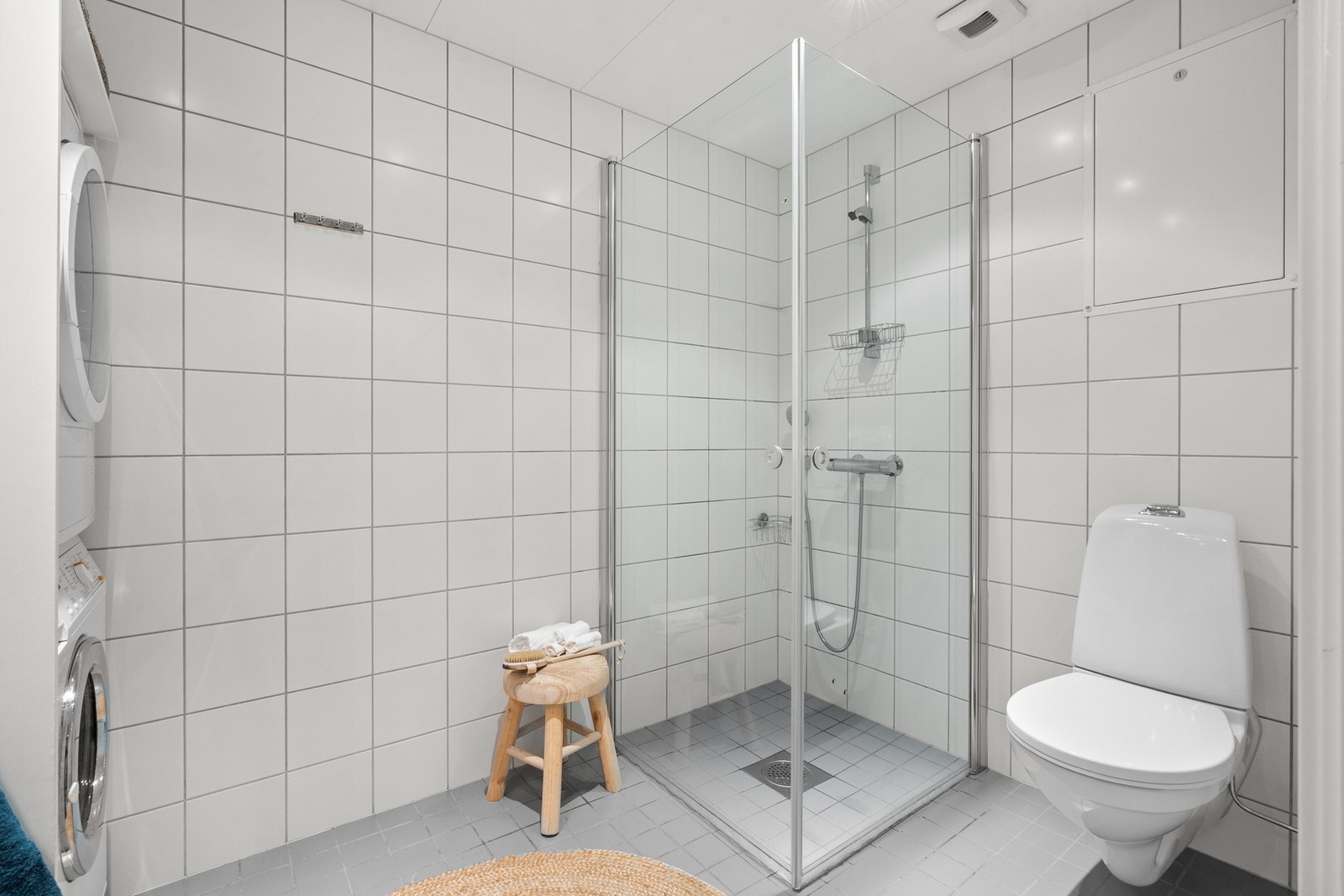 Leiligheten inneholder et romslig bad og et praktisk wc-rom. Badet fremstår som velholdt og pent, og er utstyrt med et vegghengt toalett, opplegg for vaskemaskin og et dusjhjørne med innfellbare glassdører. Blandebatteri i dusjen er fra 2025. Galleribilde