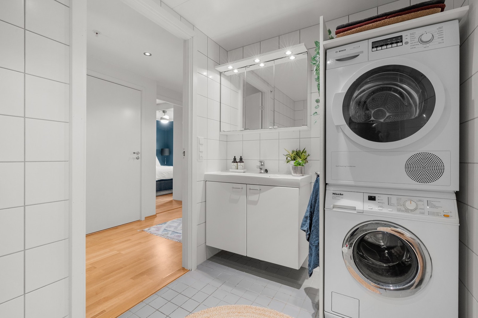 Baderomsinnredningen har hvite, glatte fronter og består av en heldekkende servant på en skapseksjon og et bredt speilskap med belysning. Galleribilde