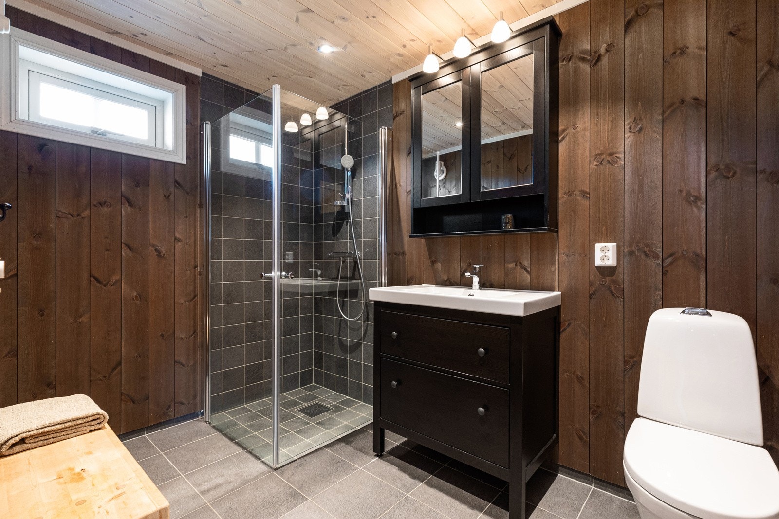 Bad to har innredning med underskuffer og speilskap, toalett og dusj Galleribilde